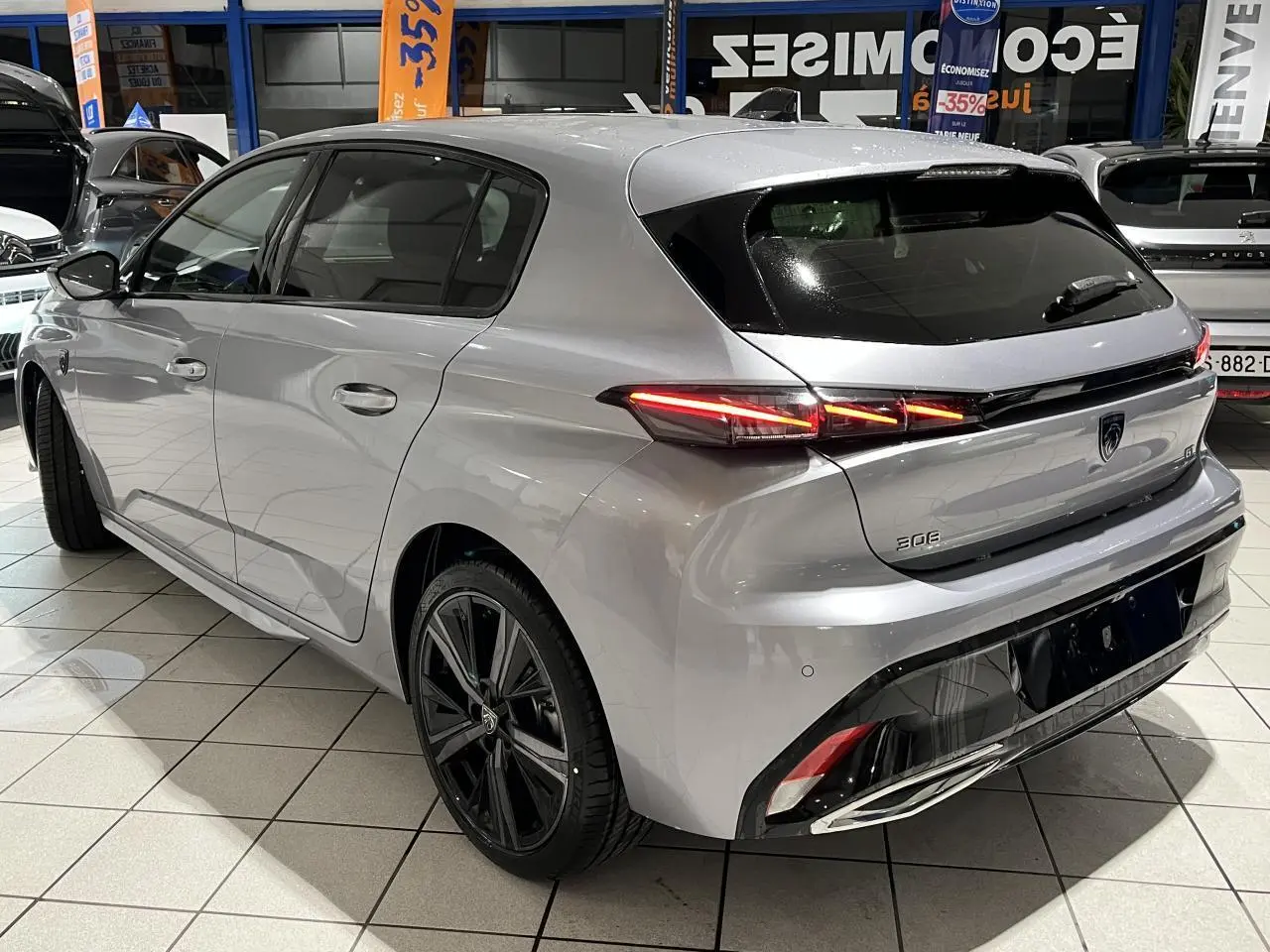 Vue 3/4 arrière droite d'une Peugeot 308 GT gris Artense avec feux arrière LED et jantes alliage 18 pouces.