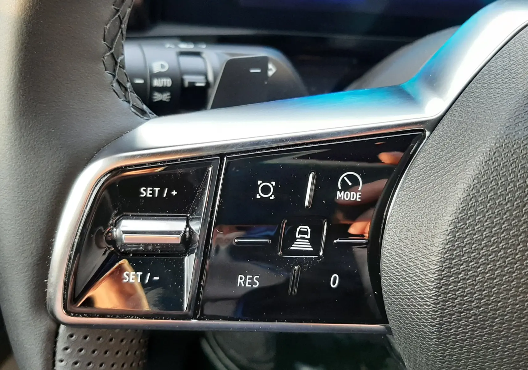 Gros plan sur les commandes à gauche du volant du Renault Austral 2025, avec boutons de régulateur et affichage numérique bleu.