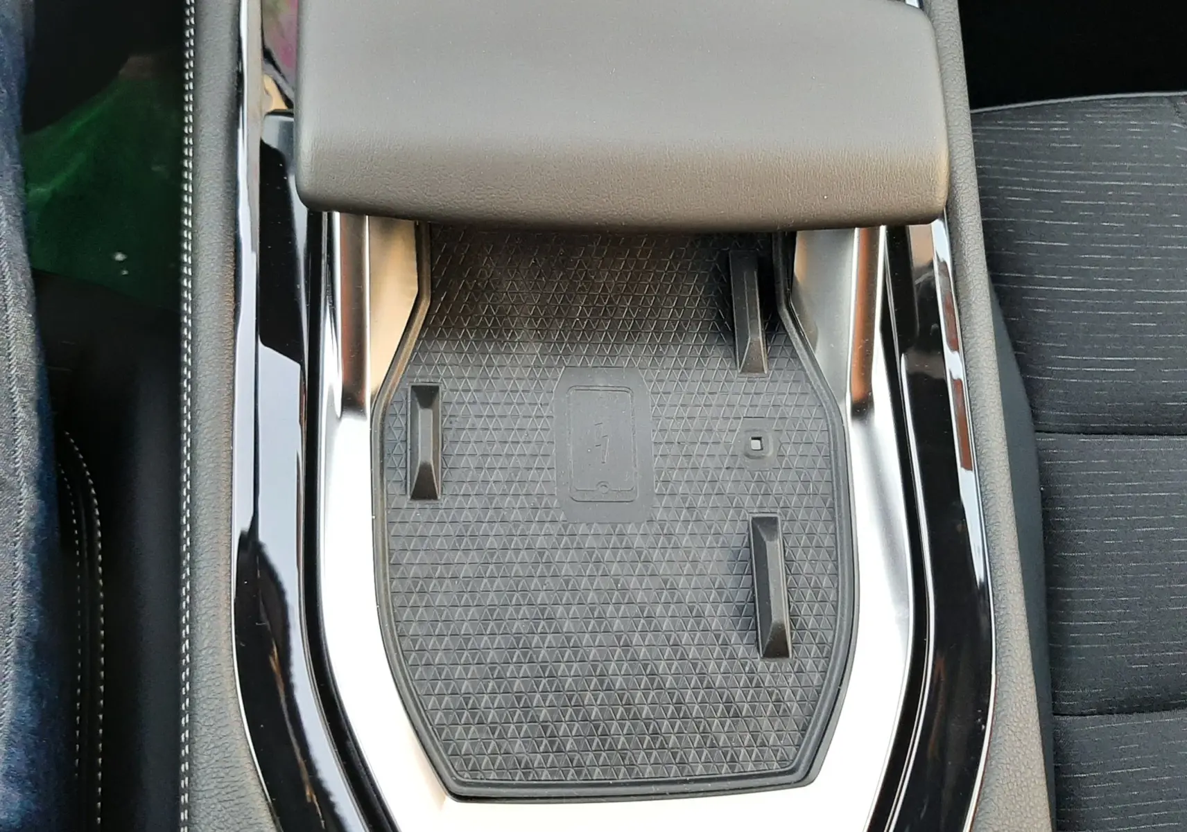 Gros plan sur le chargeur sans fil et accoudoir noir dans l'habitacle du Renault Austral blanc nacré 2025.