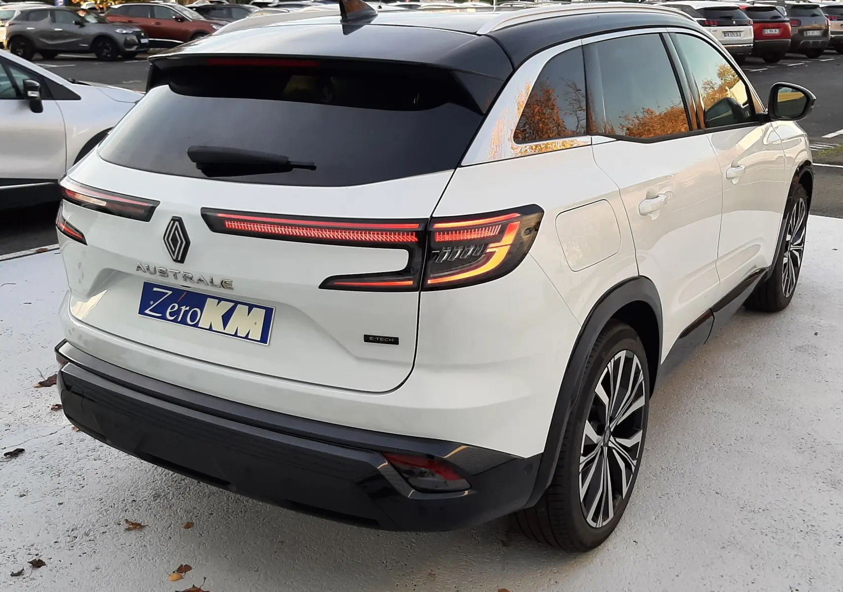 Vue 3/4 arrière droite du Renault Austral E-Tech Full Hybrid 200 Iconic blanc nacré avec toit noir et feux LED distinctifs.