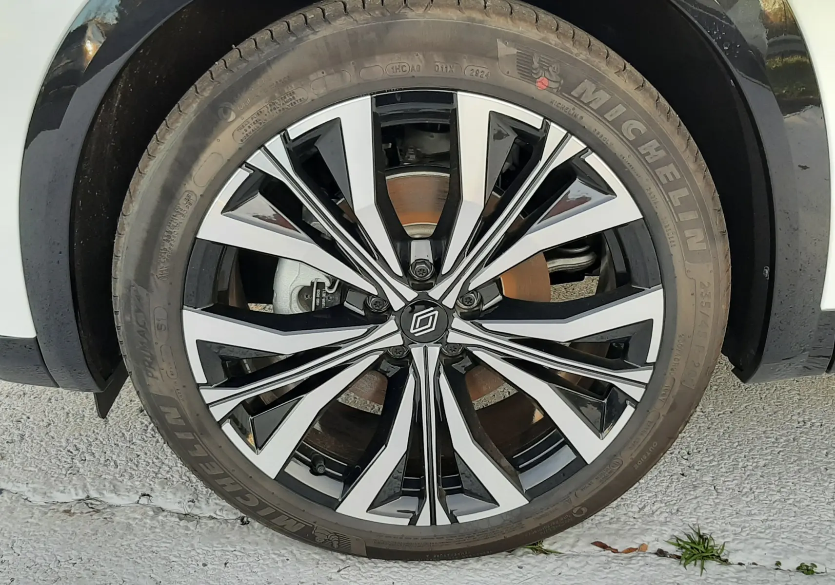 Vue arrière d'un Renault Austral 2025 blanc nacré avec toit noir, feux LED et logo central distinctif.