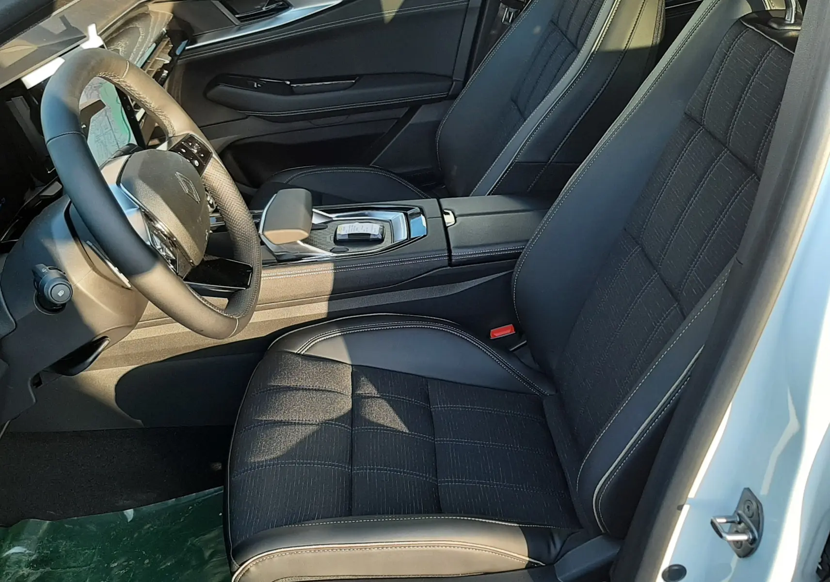 Intérieur côté conducteur du Renault Austral 2025 blanc nacré, sièges noirs en cuir et tissu avec commandes électriques.