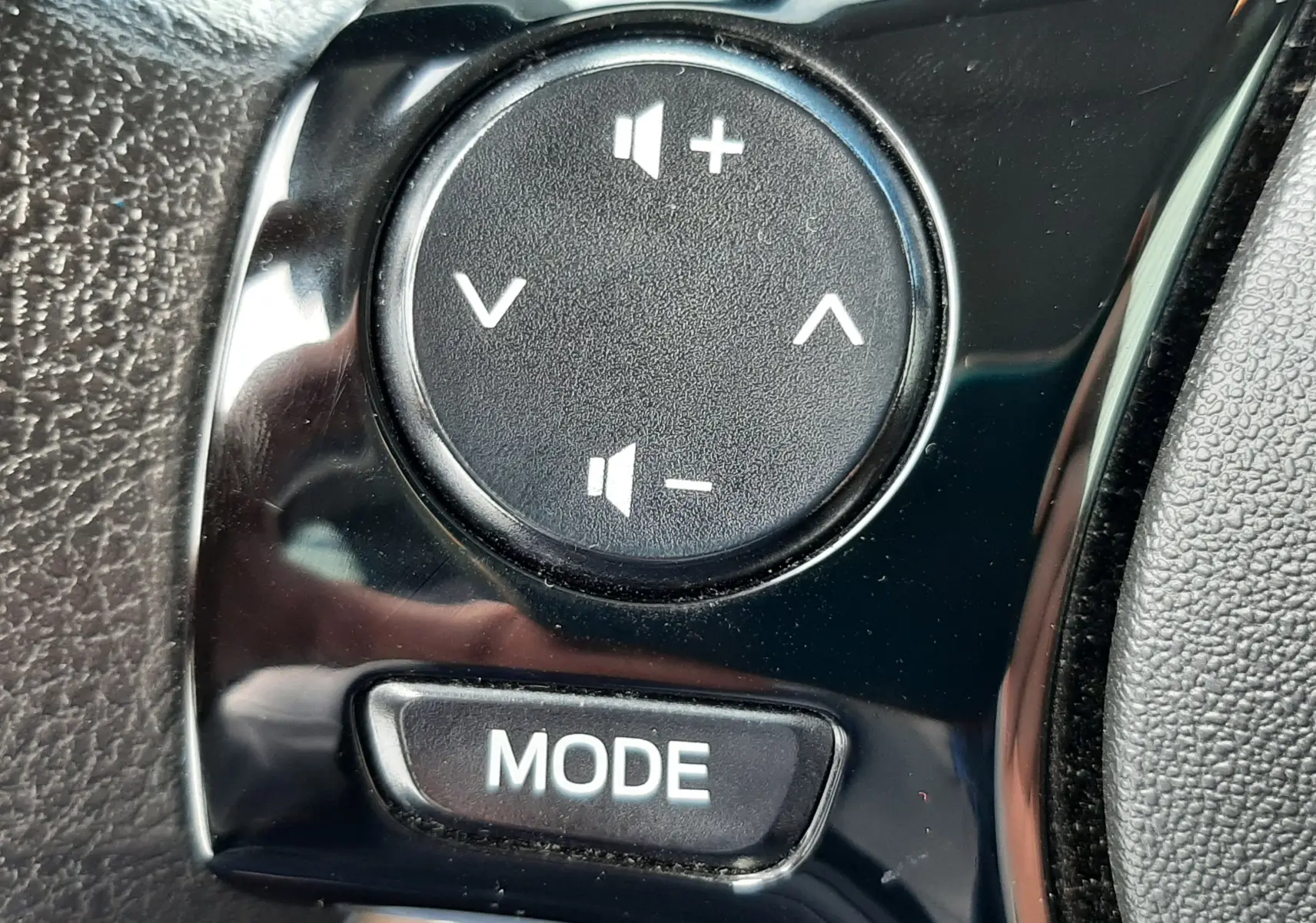 Gros plan sur les commandes de volume et mode au volant d'une Citroën C1 blanche, version 2021, intérieur noir.