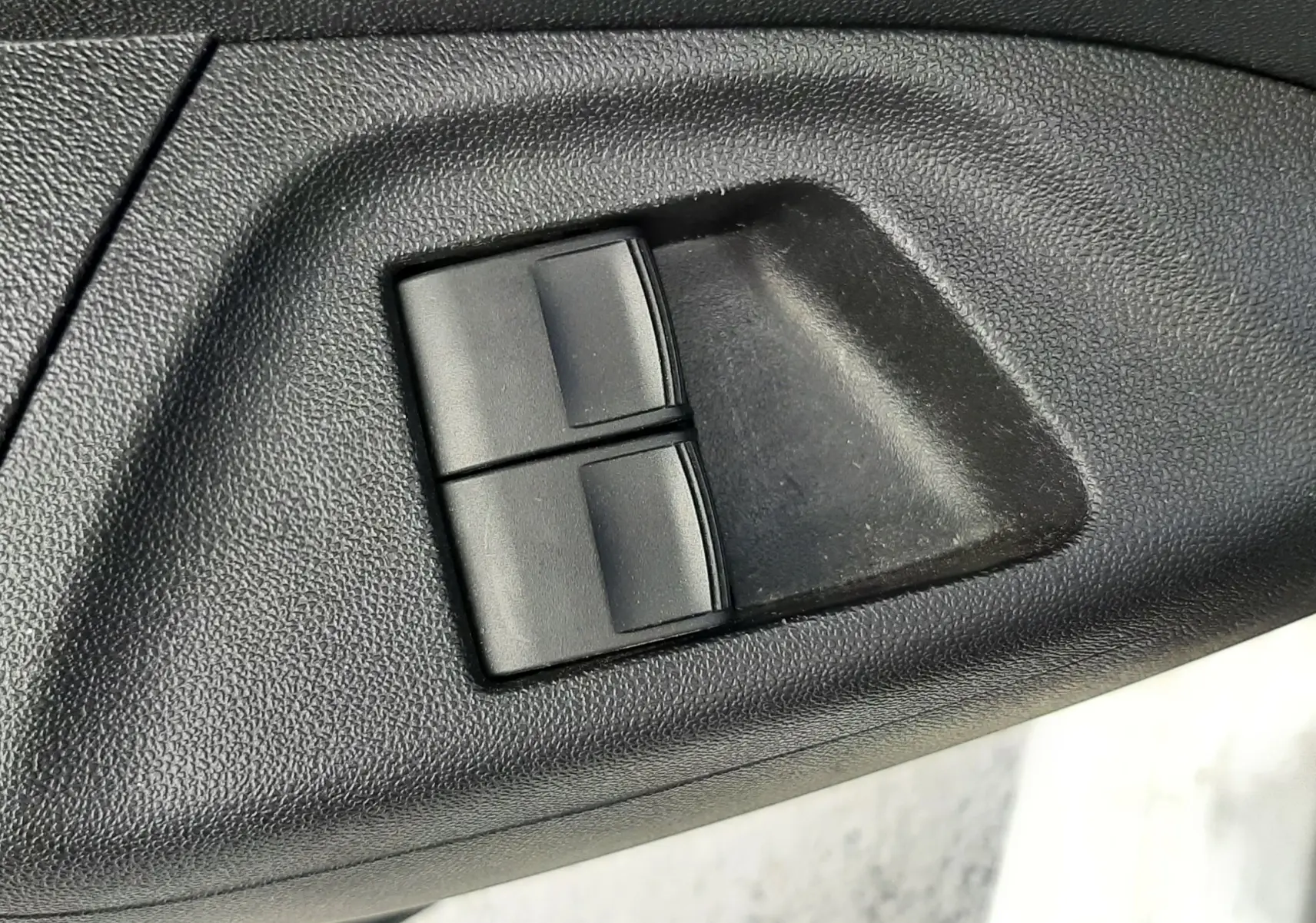 Gros plan sur les commandes de lève-vitres noirs intégrées dans la garniture intérieure noire d'une Citroën C1 blanche 2021.