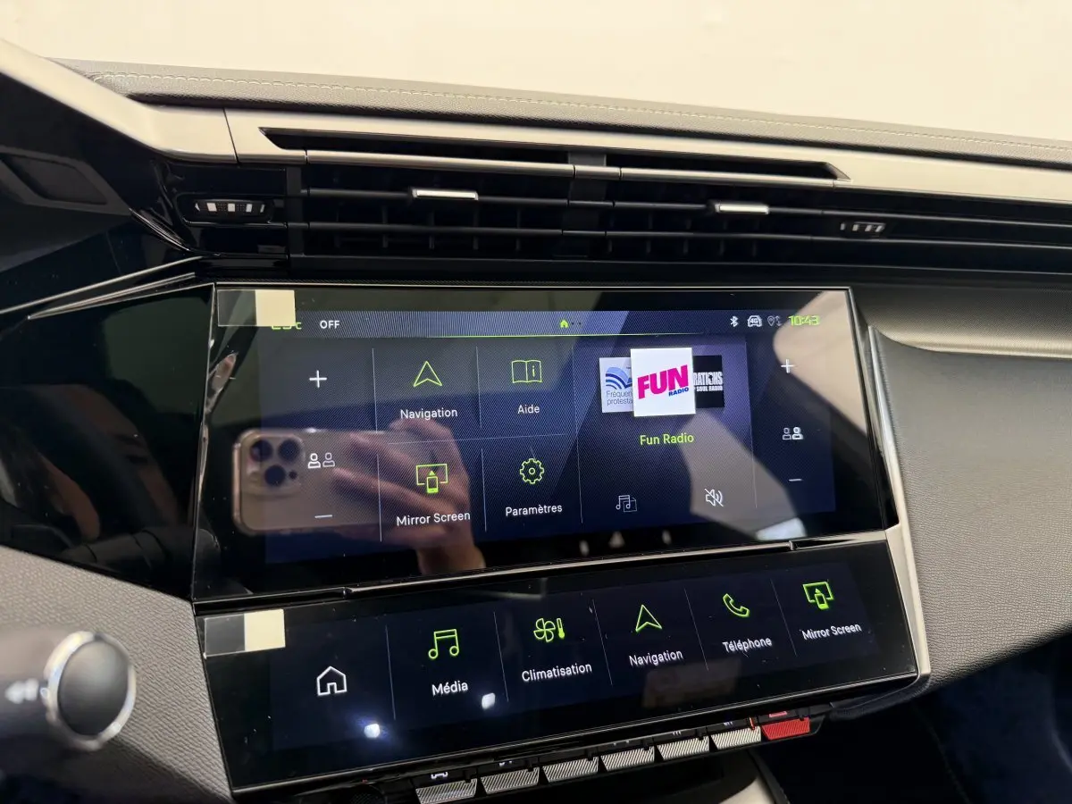 Vue rapprochée de l'écran tactile central noir du tableau de bord du Peugeot 308 Hybrid blanc, affichant le menu multimédia.