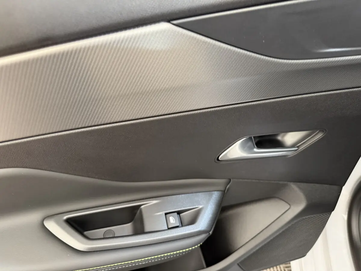 Gros plan sur la poignée intérieure et commande de verrouillage de la porte côté droit d’une Peugeot 308 Hybrid 136 e-DCS6 GT blanche.