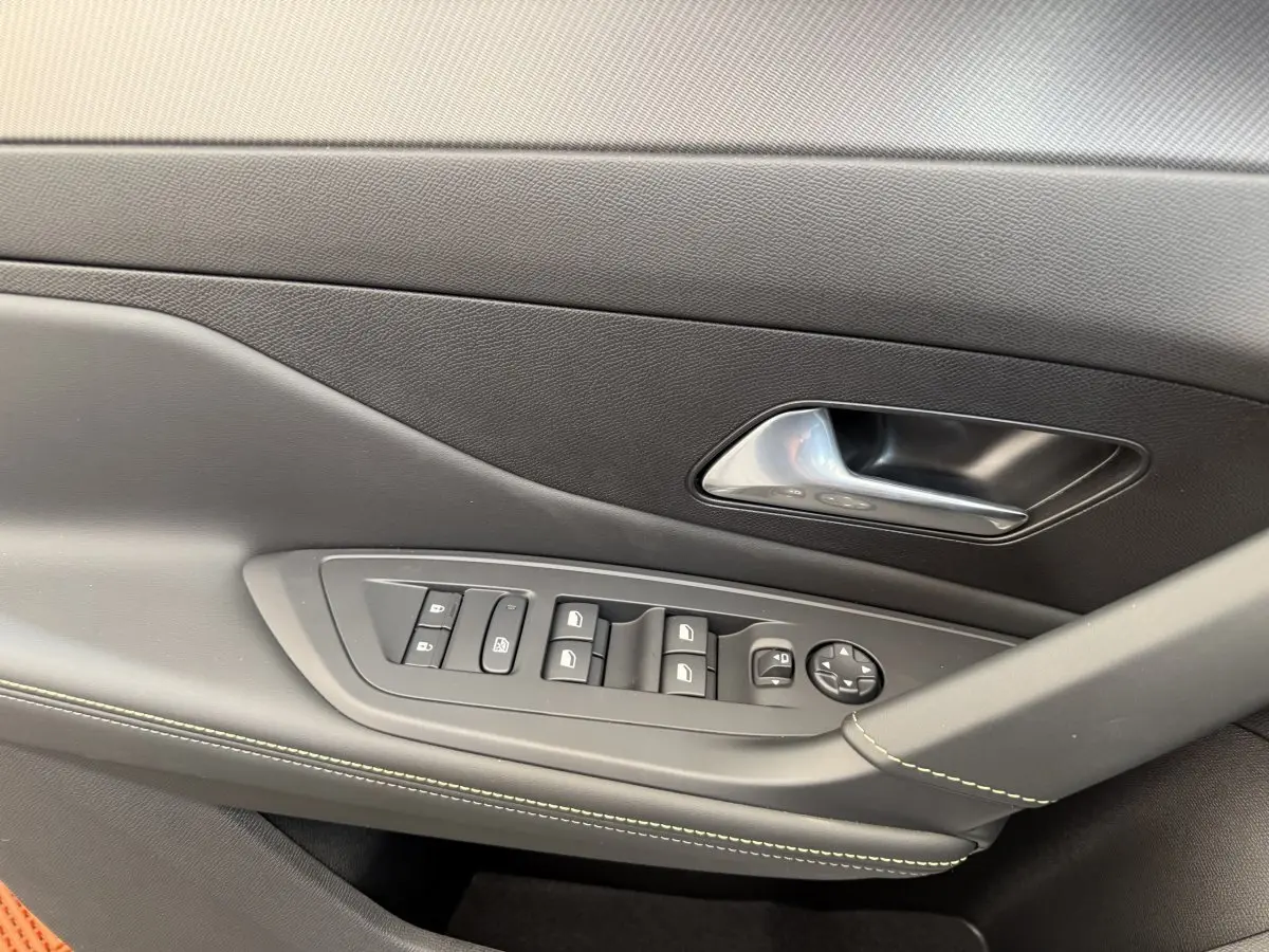 Détail de la porte côté gauche de la Peugeot 308 Hybrid 136 e-DCS6 GT 2024 avec commandes de vitres et poignée argentée.
