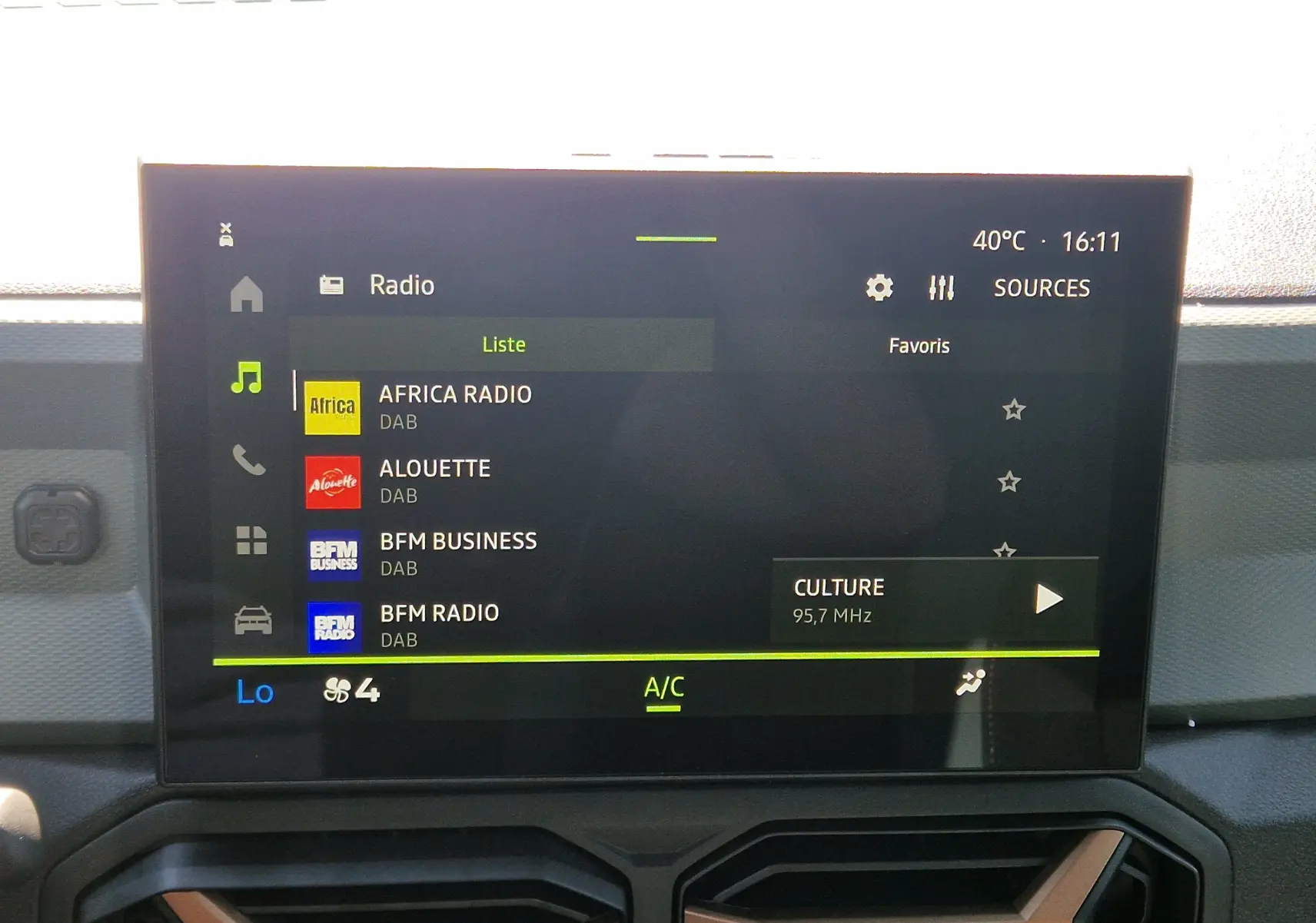 Écran central du tableau de bord du Dacia Duster 2026 affichant la liste des radios DAB avec climatisation à 16h11.