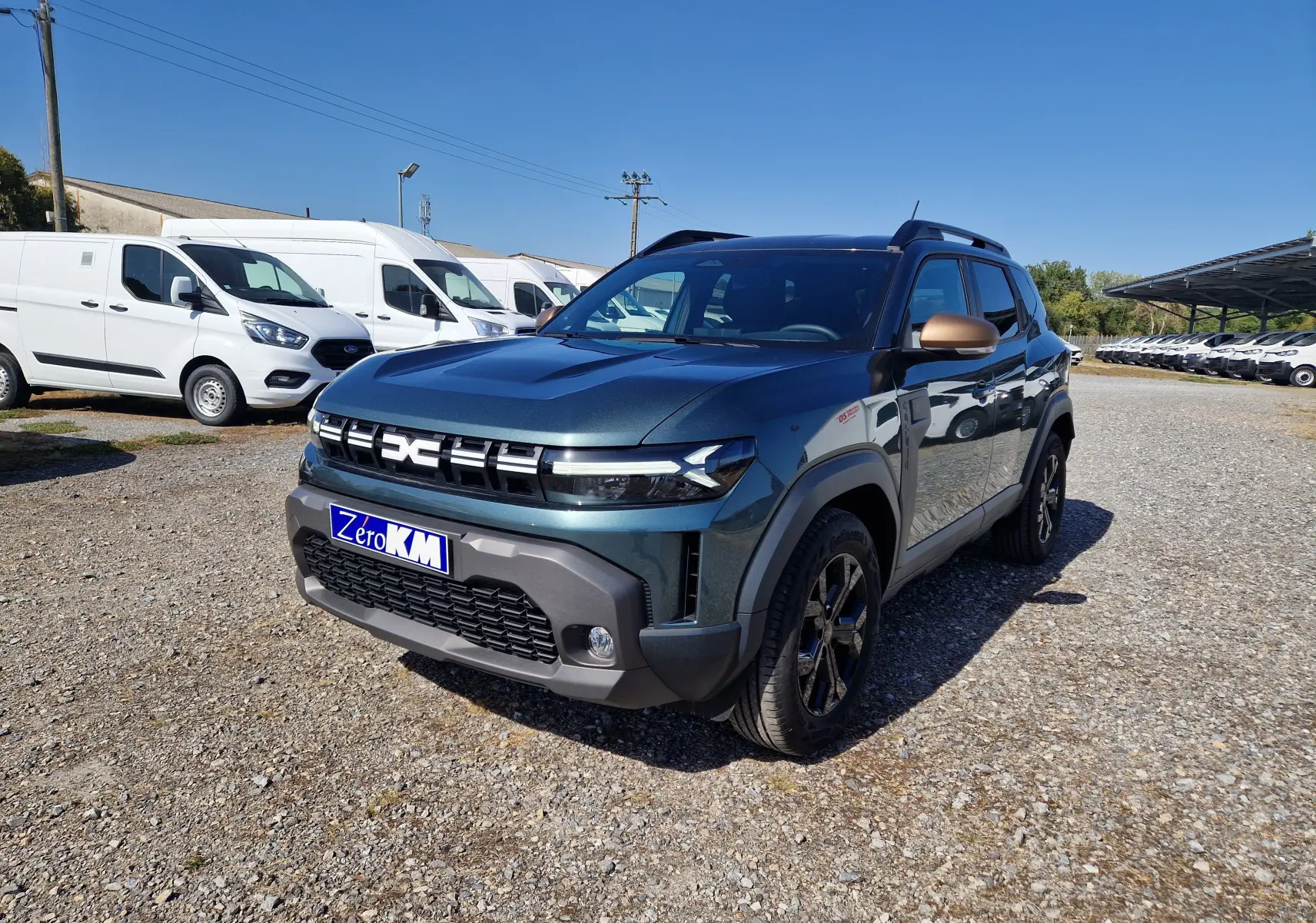 Dacia Duster 1.8 Hybrid 155 Extreme vert cèdre en 3/4 avant droit, avec détails bronze sur les rétroviseurs.