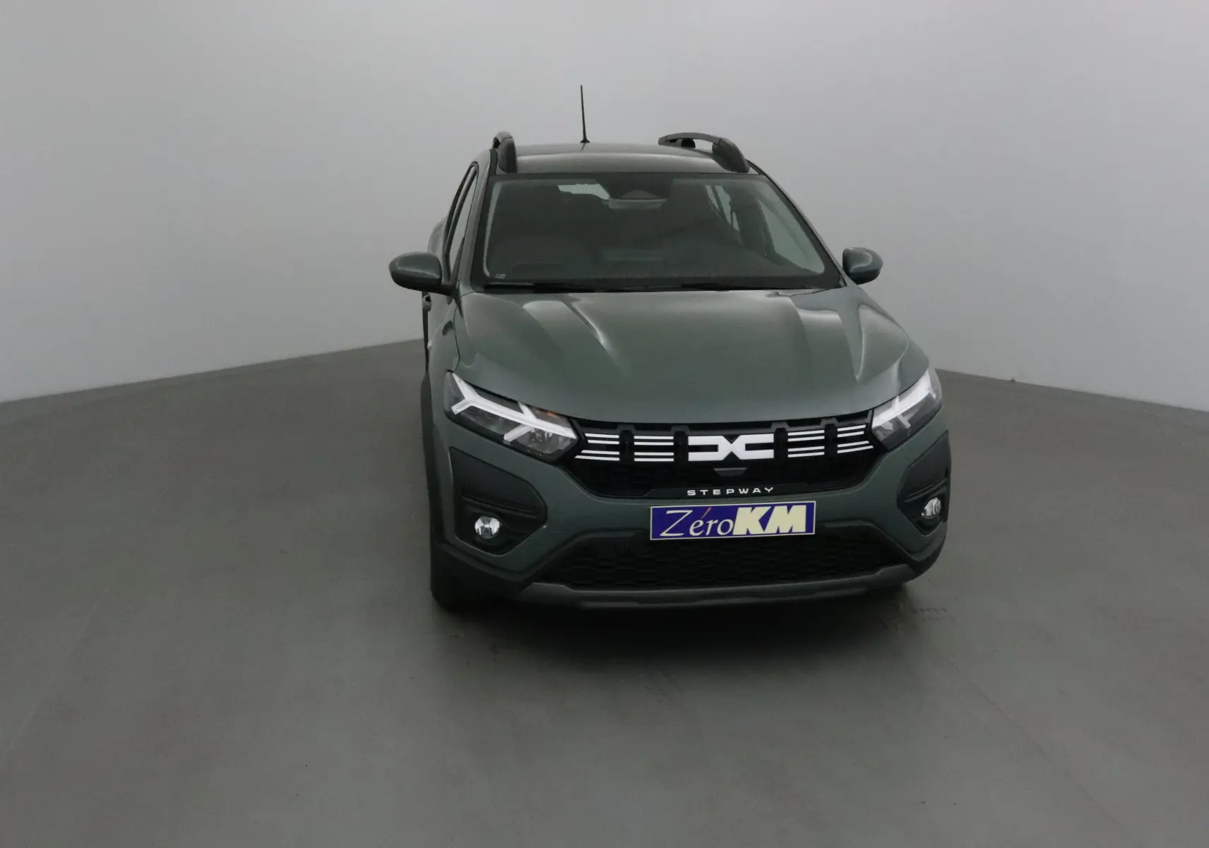 Vue frontale d'une Dacia Sandero Stepway 2025 kaki Kichen avec calandre noire et phares LED distinctifs.
