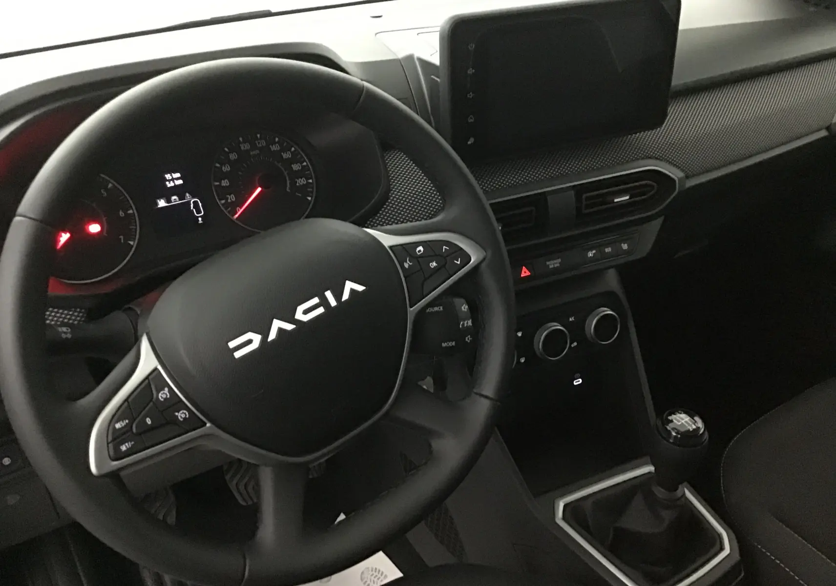 Vue intérieure du tableau de bord et volant Dacia Sandero Stepway 2025, avec console centrale et levier de vitesses manuel.