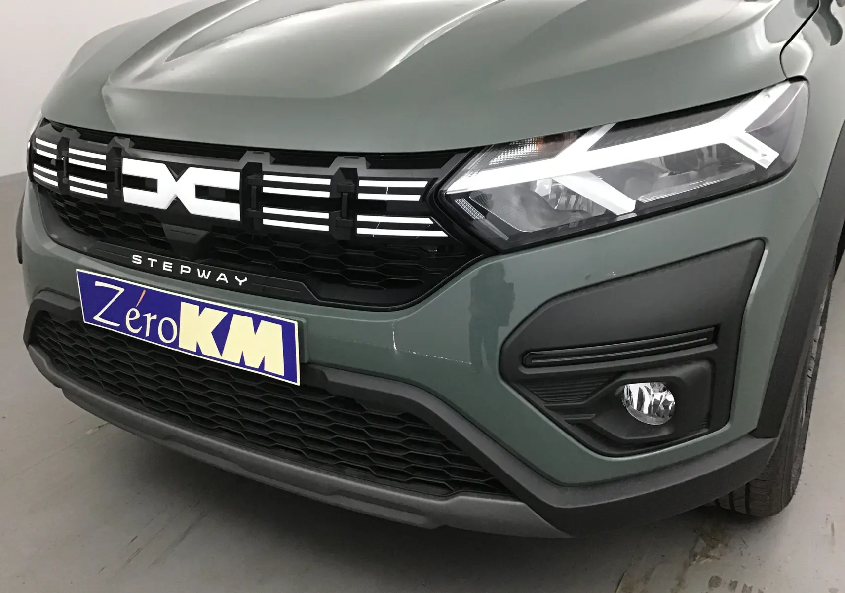 Vue avant droite d'une Dacia Sandero Stepway 2025 kaki Kichen avec signature lumineuse LED et calandre noire.
