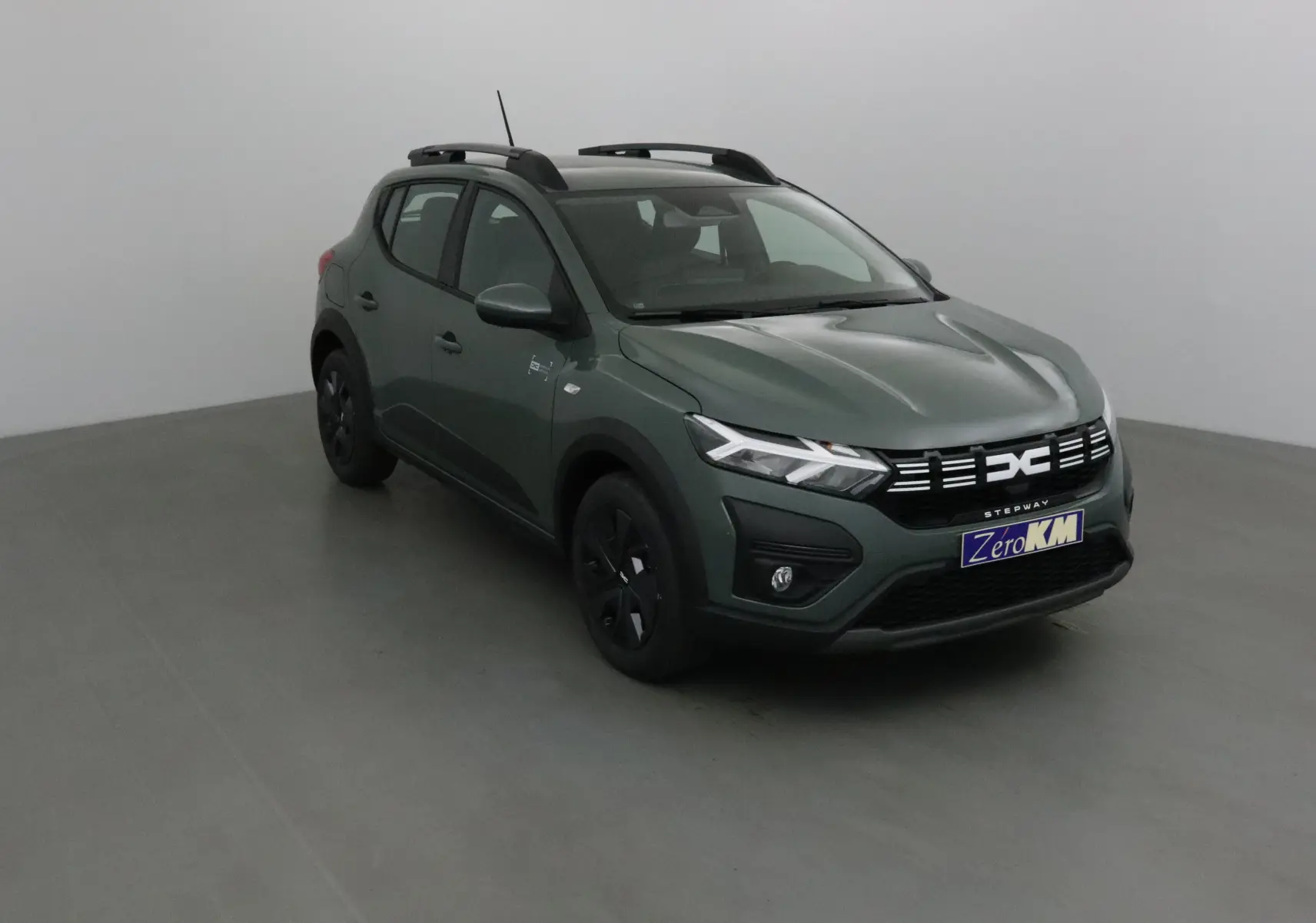 Dacia Sandero Stepway 2025 kaki Kichen en 3/4 avant droit avec barres de toit et jantes noires.