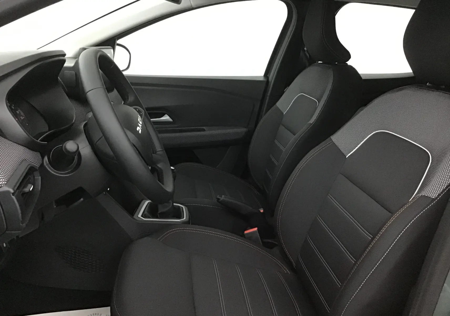 Vue intérieure côté conducteur de la Dacia Sandero Stepway 2025, sièges noirs avec surpiqûres blanches et volant multifonction.