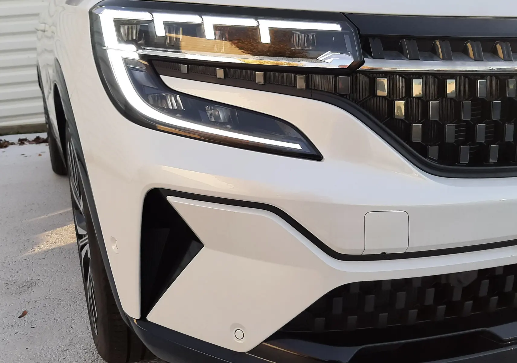 Vue arrière ouverte du coffre d'un Renault Austral blanc nacré avec toit noir, version hybride 2025, sans chargement.