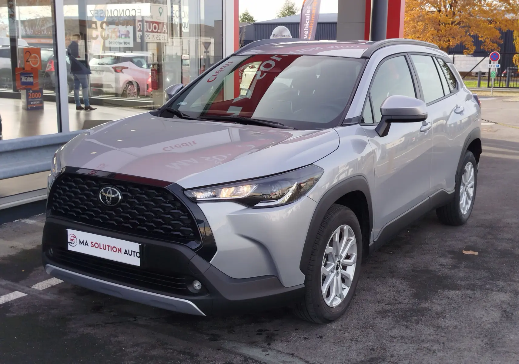 Toyota Corolla Cross gris acier vue 3/4 avant droit, avec calandre noire et jantes alliage argentées.