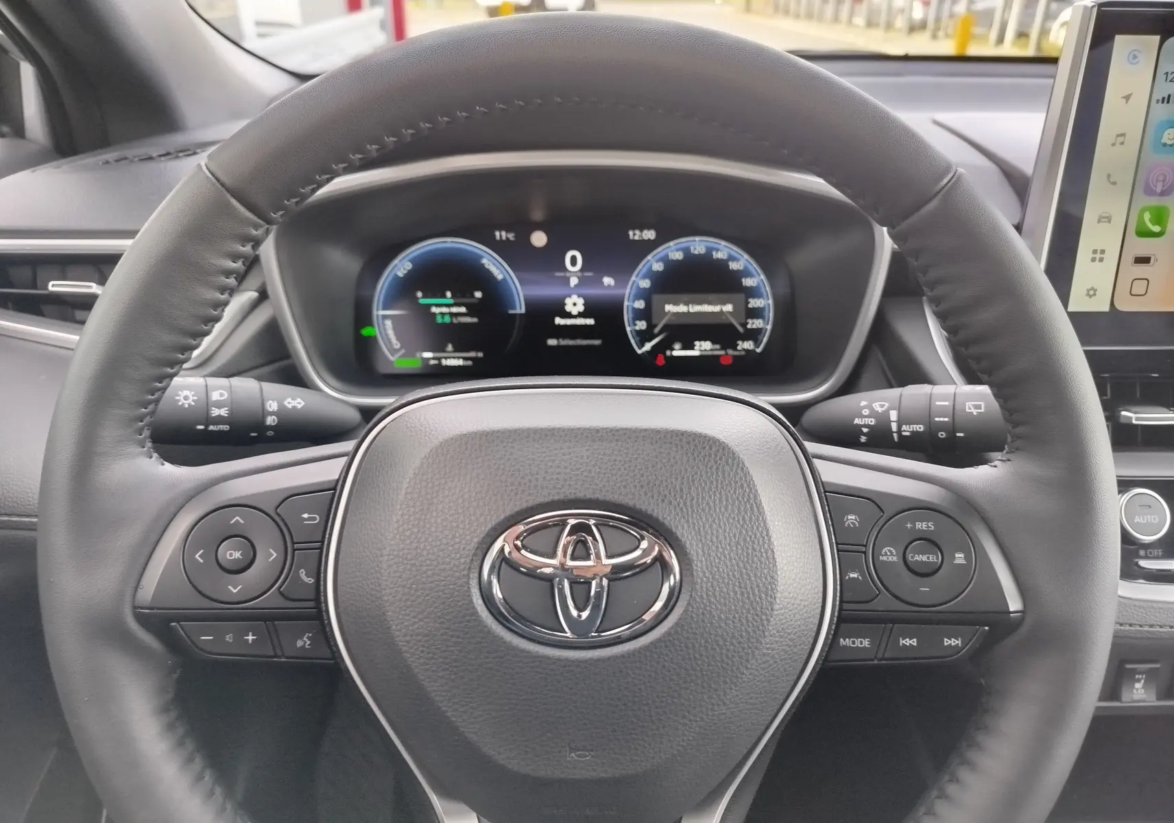 Vue rapprochée du volant noir et du tableau de bord numérique d'une Toyota Corolla Cross 2025 hybride.