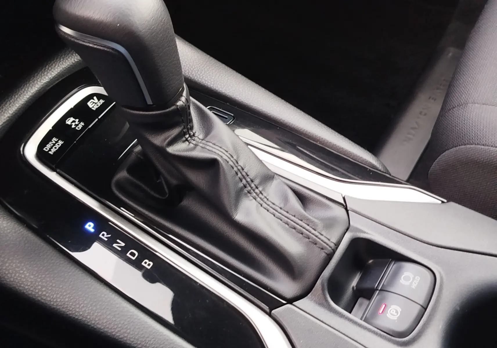 Gros plan sur la console centrale du Toyota Corolla Cross 2025, levier de vitesse automatique en cuir noir et commandes de mode de conduite.