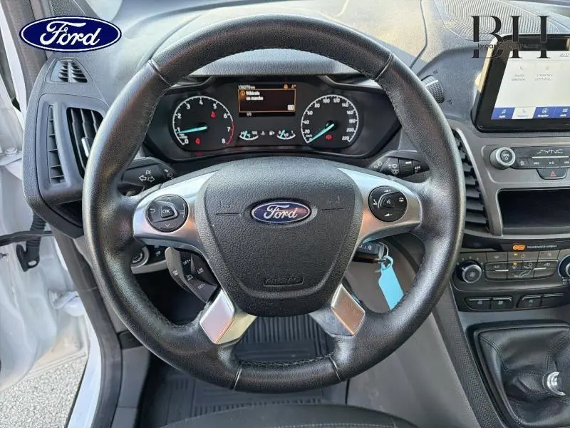 Vue centrée sur le volant multifonction noir du Ford Transit Connect blanc glacier, avec tableau de bord et écran tactile visibles.