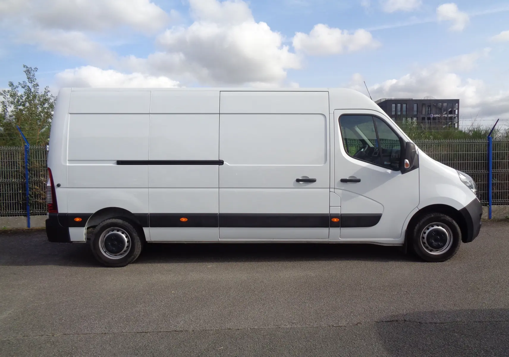 Profil droit d’un fourgon Opel Movano blanc polaire 2022 avec bande noire et feux latéraux orange.