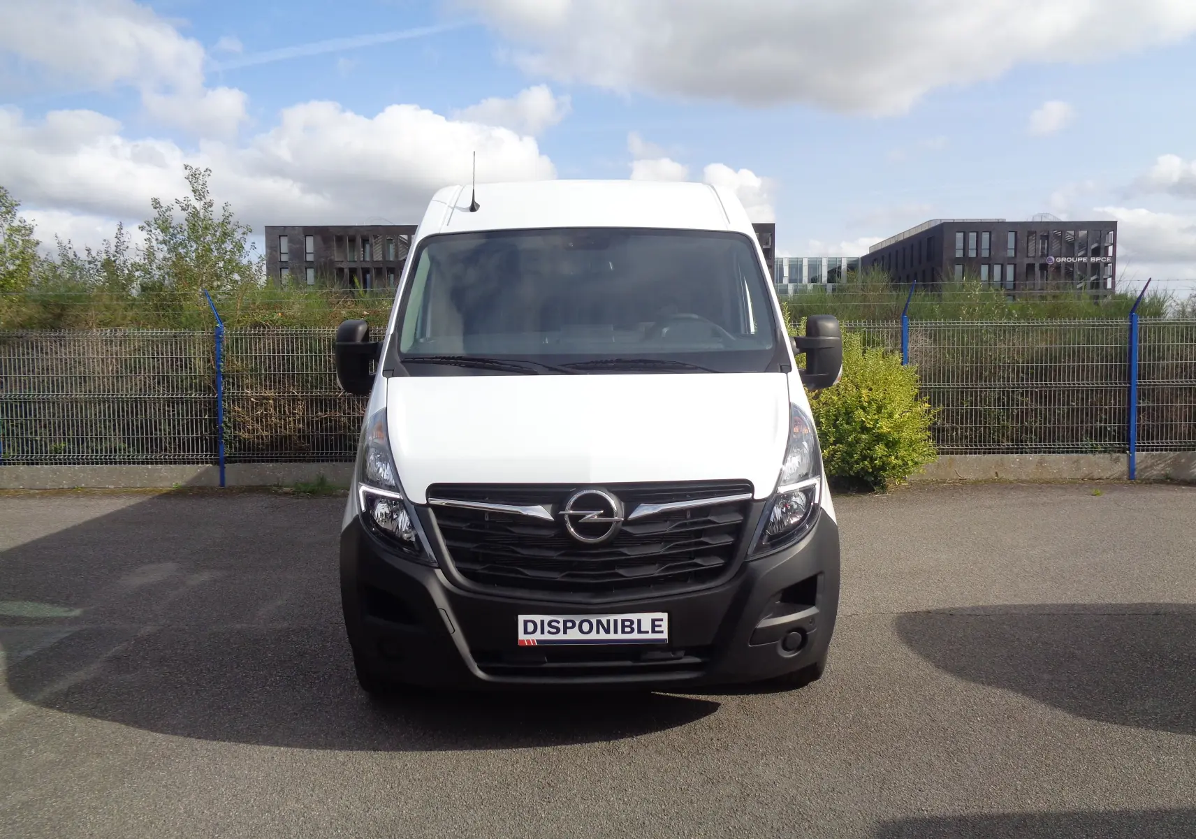 Vue frontale d'un Opel Movano Fourgon blanc polaire avec calandre noire et plaque "DISPONIBLE" visible.