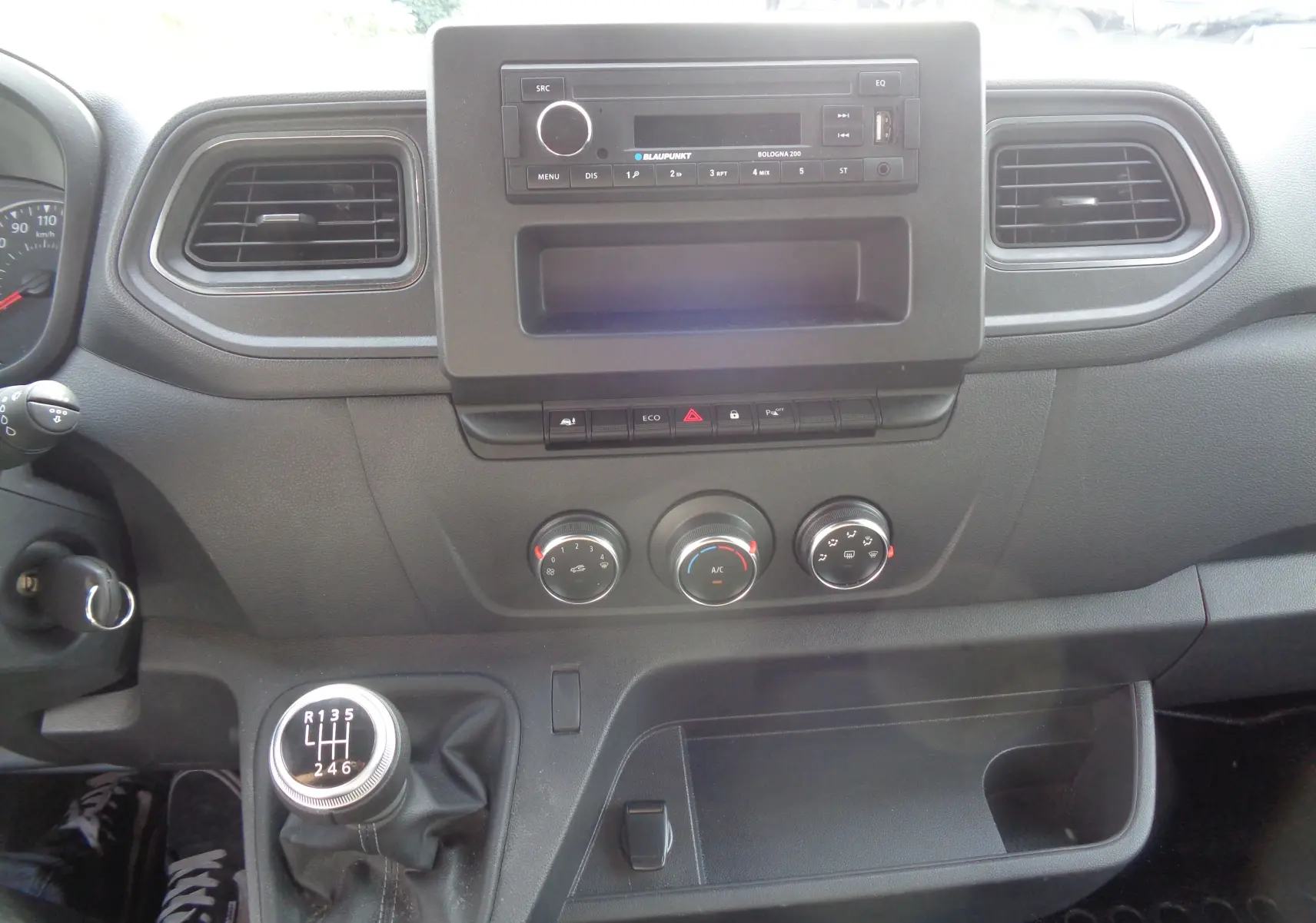 Tableau de bord noir de l'Opel Movano Fourgon 2022 avec commandes manuelles de climatisation et levier de vitesses à six rapports.