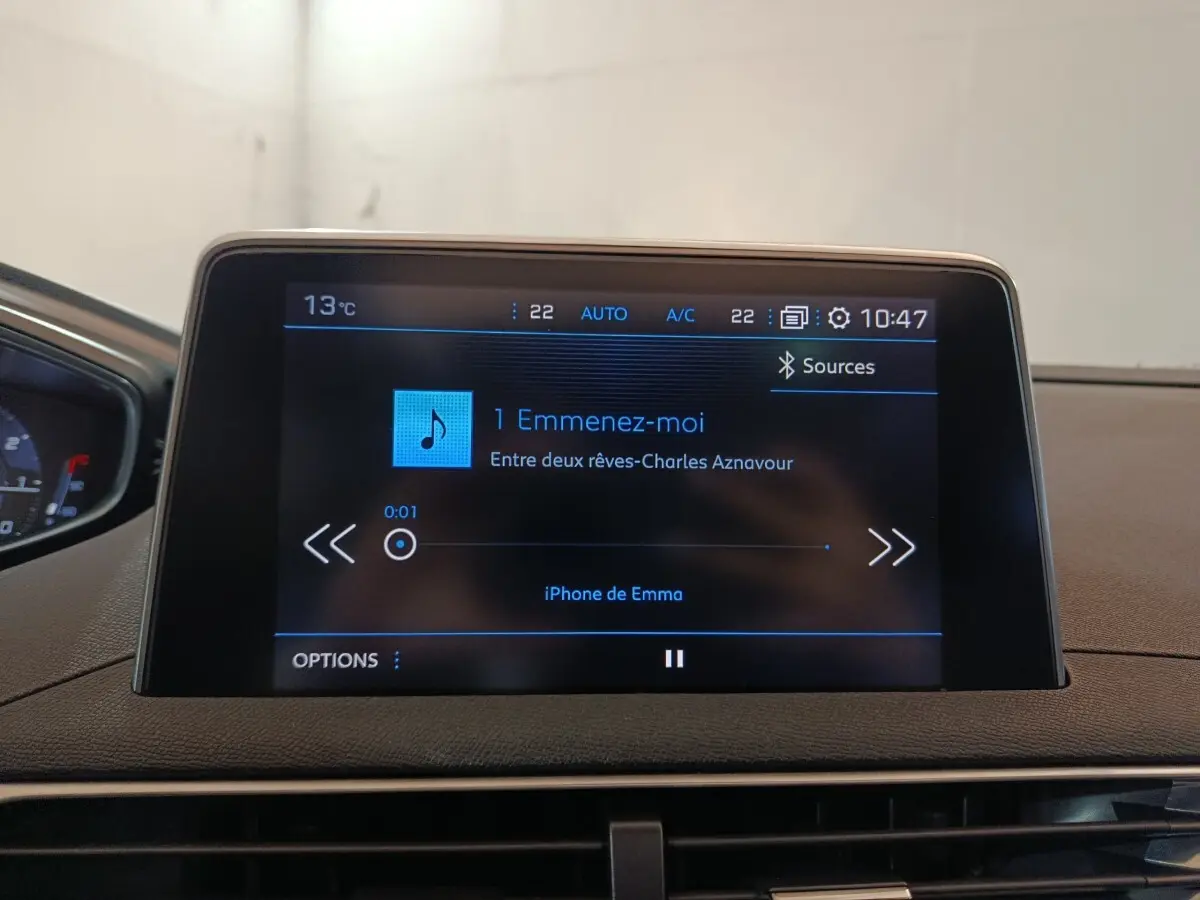 Écran tactile central du tableau de bord du Peugeot 3008 blanc, affichant une musique en cours de lecture.