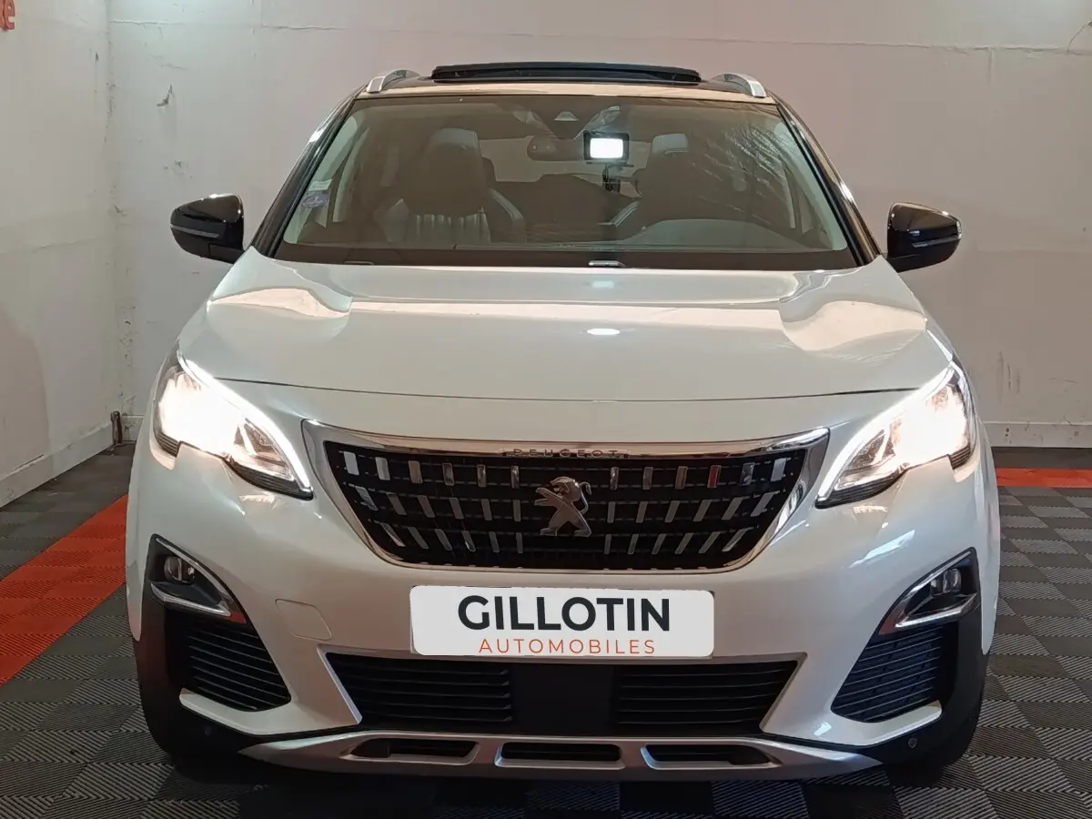 Vue frontale d'un Peugeot 3008 blanc avec phares allumés et calandre noire distinctive.