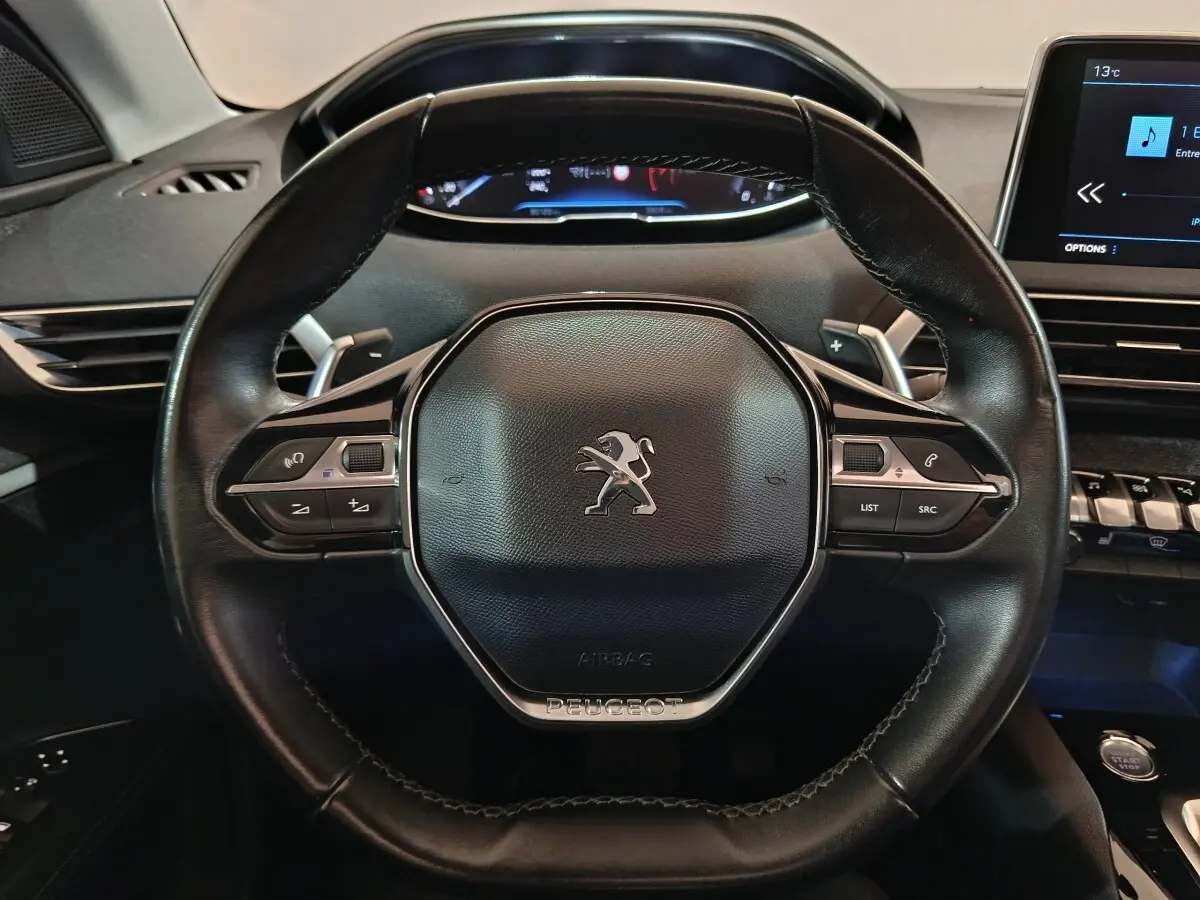 Vue rapprochée du volant cuir noir du Peugeot 3008 2019 avec commandes multifonctions et tableau de bord digital.