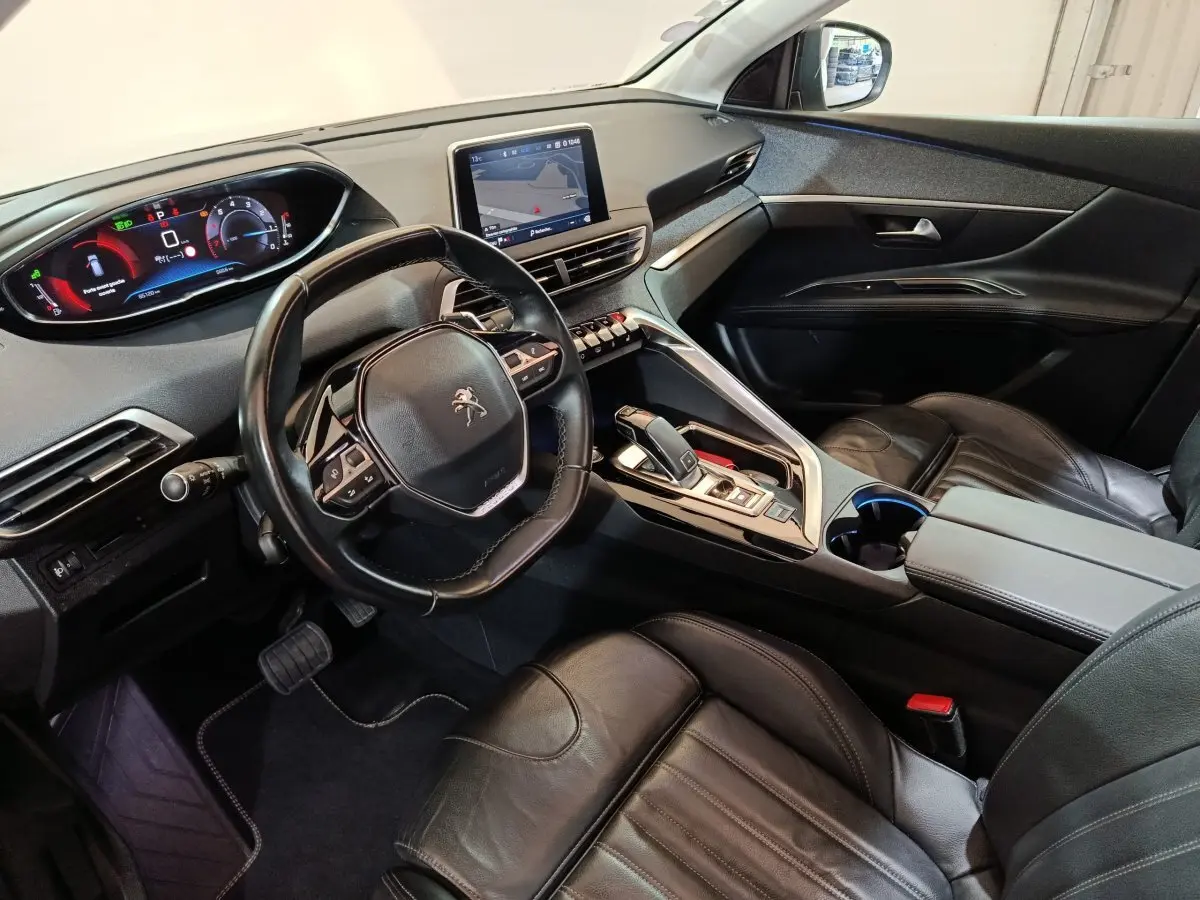 Vue intérieure côté conducteur du Peugeot 3008 avec volant cuir, écran tactile central et sièges en cuir noirs.