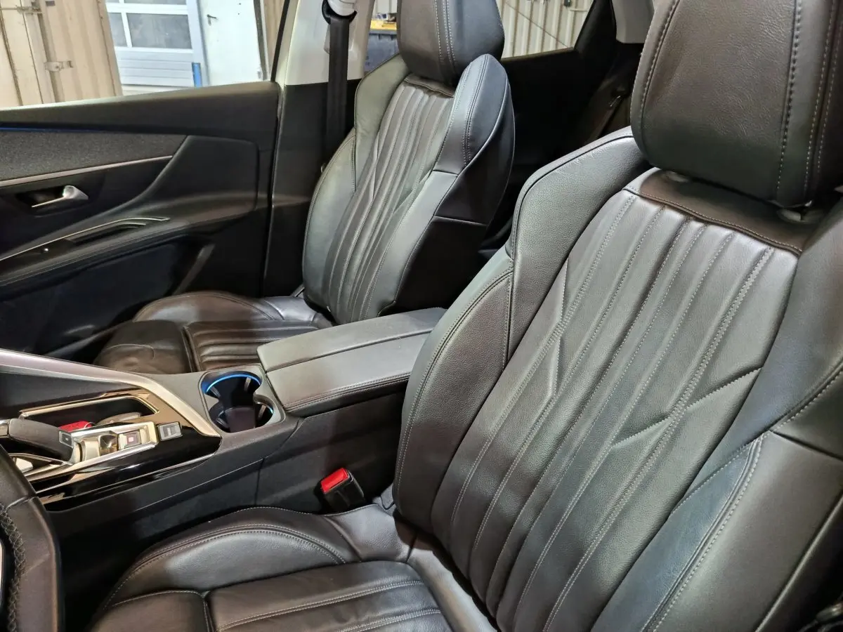 Intérieur du Peugeot 3008 Puretech 130, vue rapprochée des sièges avant en cuir noir et console centrale.