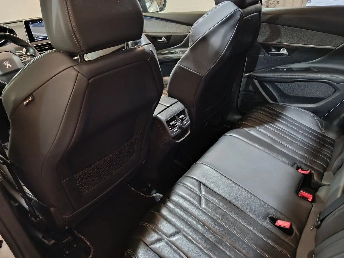 Vue intérieure arrière du Peugeot 3008 blanc, sièges en cuir noir et console centrale avec aérateurs arrière.
