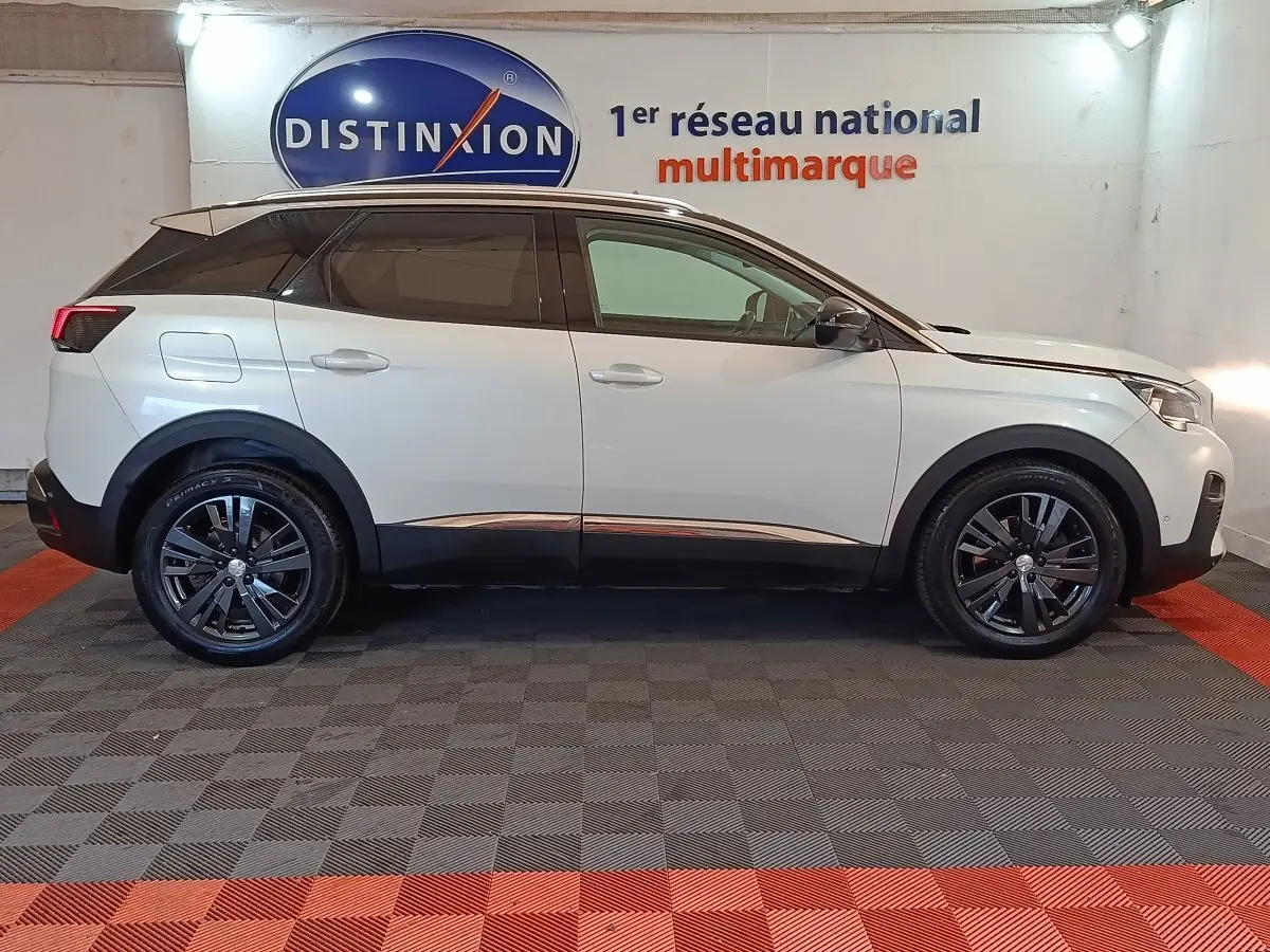 Profil droit d’un Peugeot 3008 blanc 2019 Puretech Allure avec jantes noires et toit noir dans un showroom.