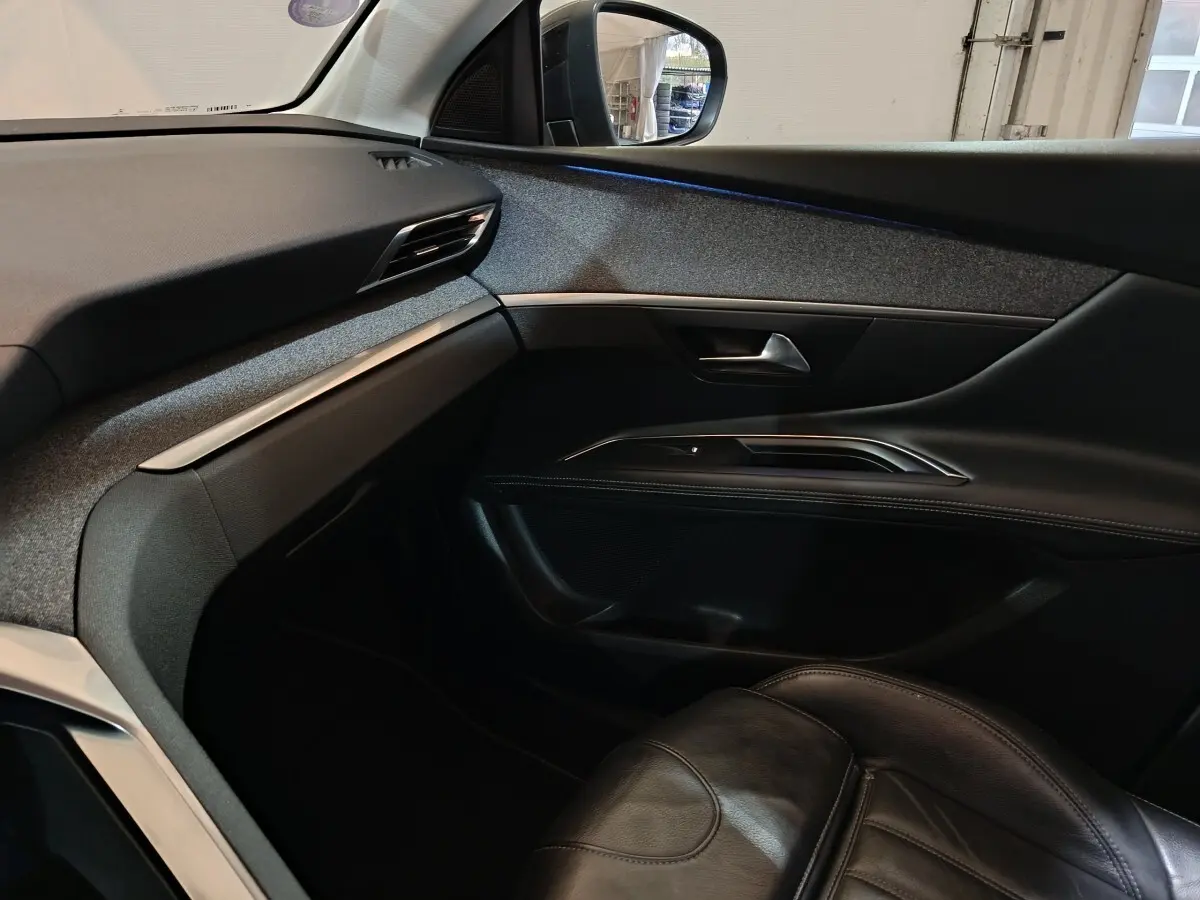 Vue intérieure côté passager du Peugeot 3008 blanc, montrant la portière et le tableau de bord avec finitions noires et grises.