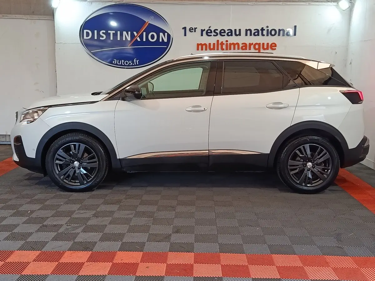 Profil droit du Peugeot 3008 blanc de 2019, avec jantes noires et toit noir contrastant, en intérieur showroom.