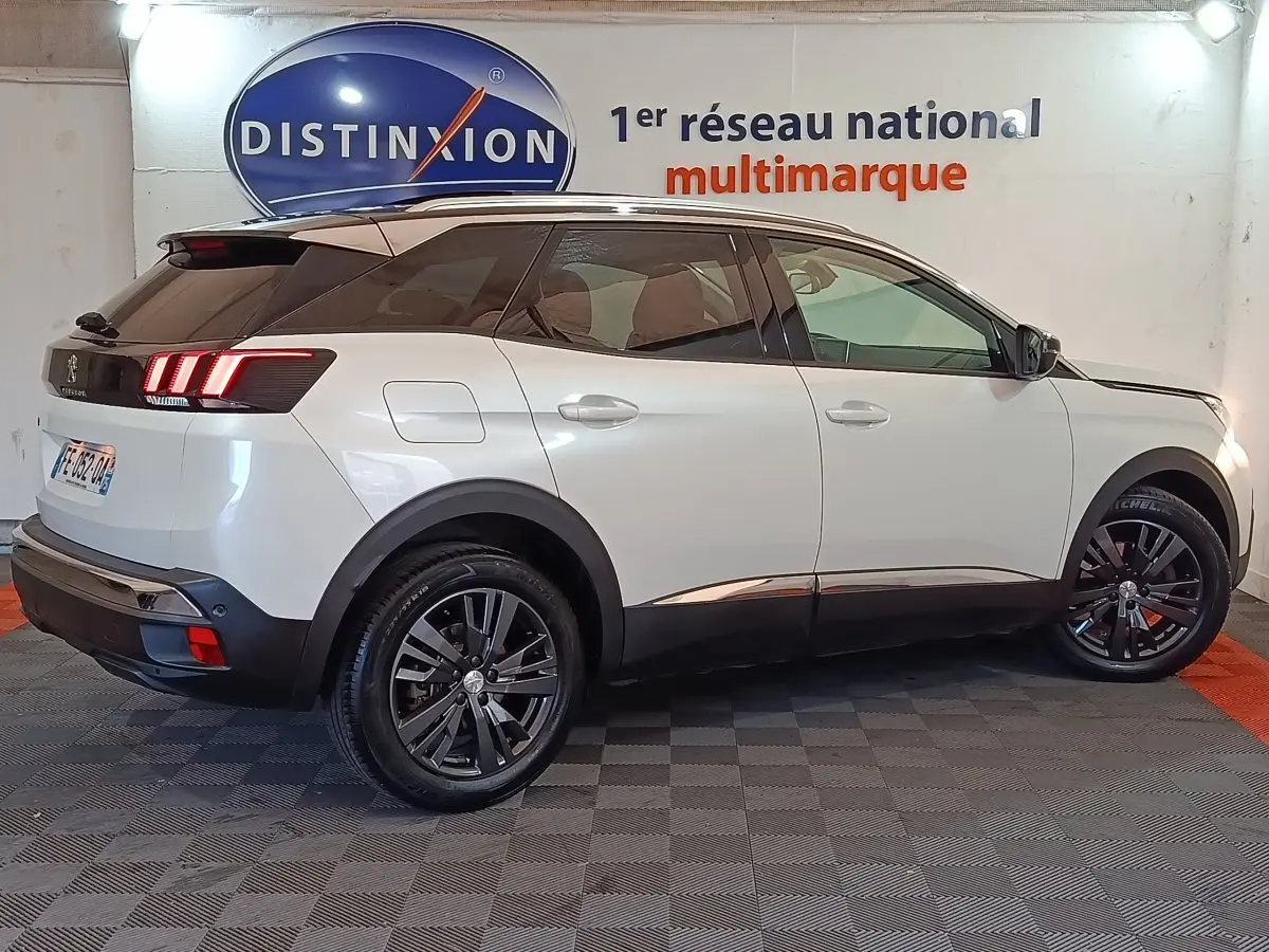 Peugeot 3008 blanc vue de profil côté droit, avec jantes noires et feux arrière LED allumés.