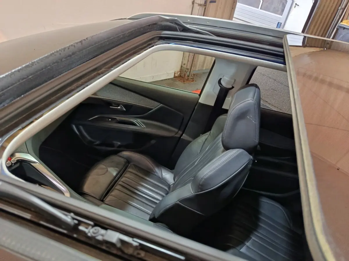 Vue plongeante par le toit ouvrant sur l'intérieur noir cuir côté conducteur du Peugeot 3008 blanc de 2019.
