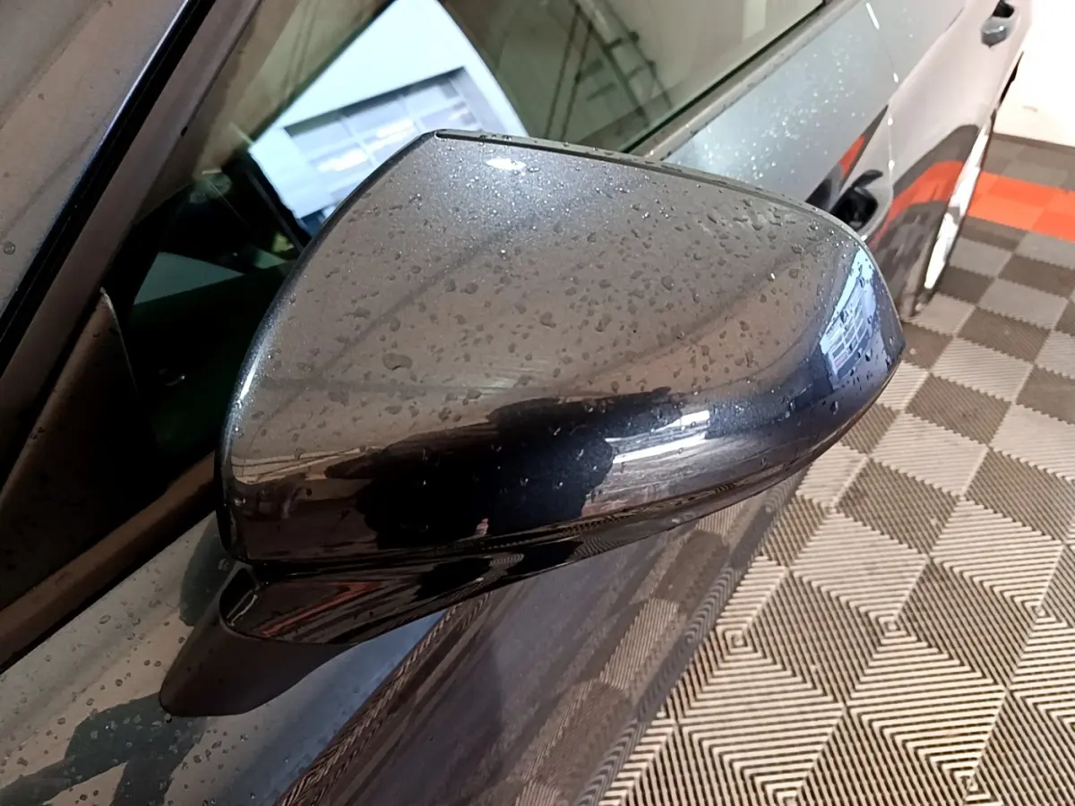 Rétroviseur droit gris clair de la SEAT LEON 2023 avec gouttes d'eau, vue rapprochée côté conducteur.