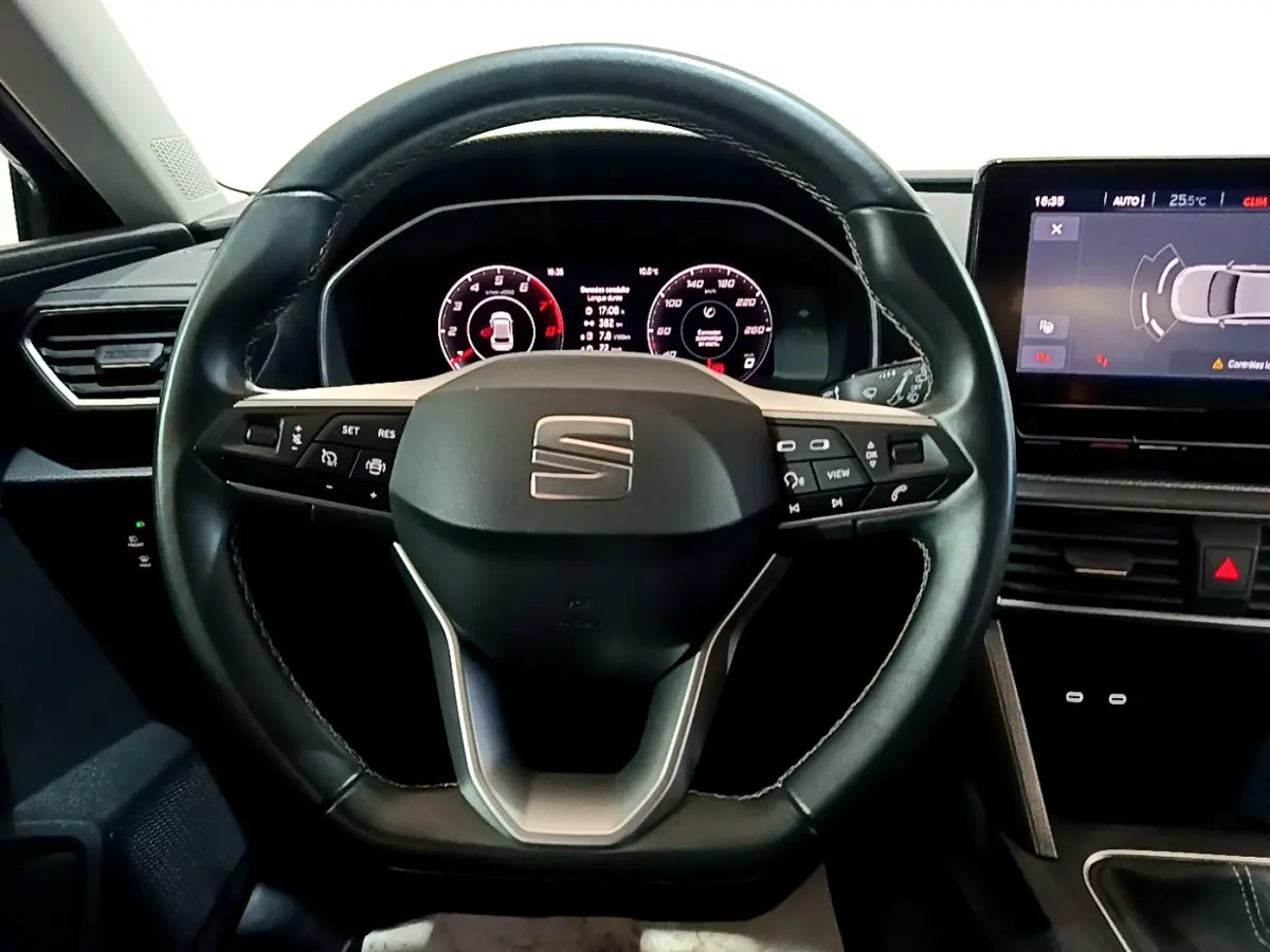 Vue rapprochée du volant en cuir noir et du tableau de bord numérique du SEAT Leon 2023, avec écran tactile latéral.