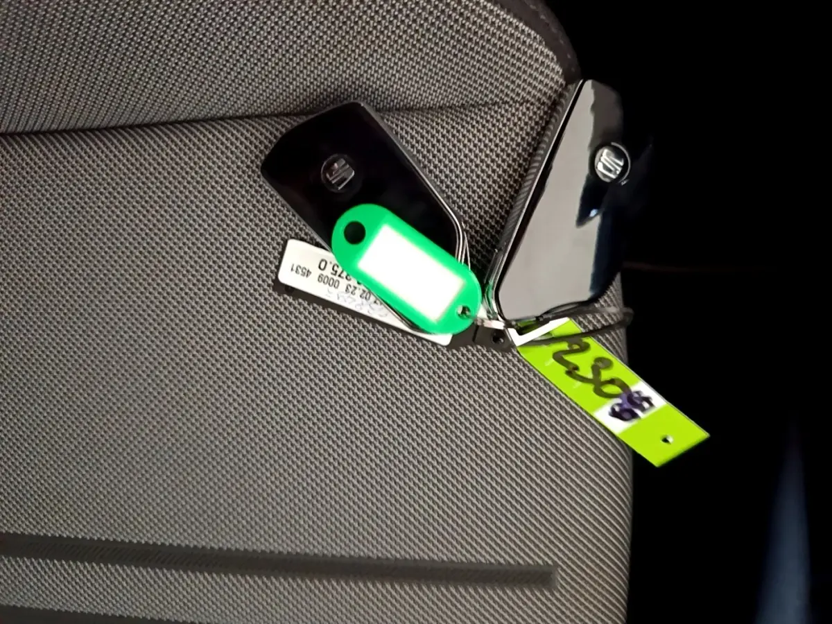 Clé de voiture SEAT LEON 2023 posée sur un siège tissu gris clair, avec porte-clés vert fluo visible.