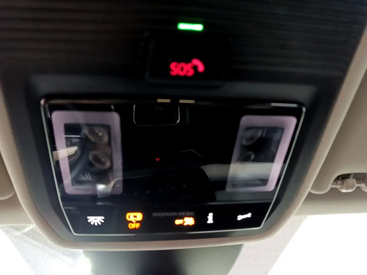 Vue en gros plan du panneau de commandes au plafond avec bouton SOS rouge et éclairage ambiant sur SEAT Leon gris clair 2023.