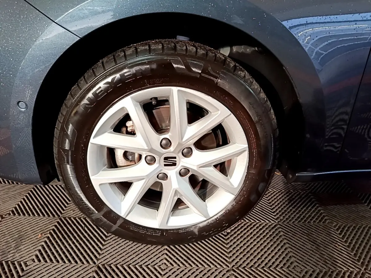 Gros plan sur la roue avant droite gris clair d'une SEAT LEON 2023 avec jante alliage et logo central SEAT.
