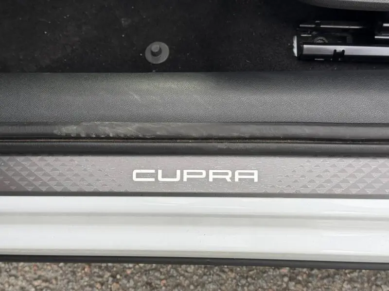 Gros plan sur la plaque de seuil de porte avec logo CUPRA sur un CUPRA Formentor blanc Nevada métallisé.