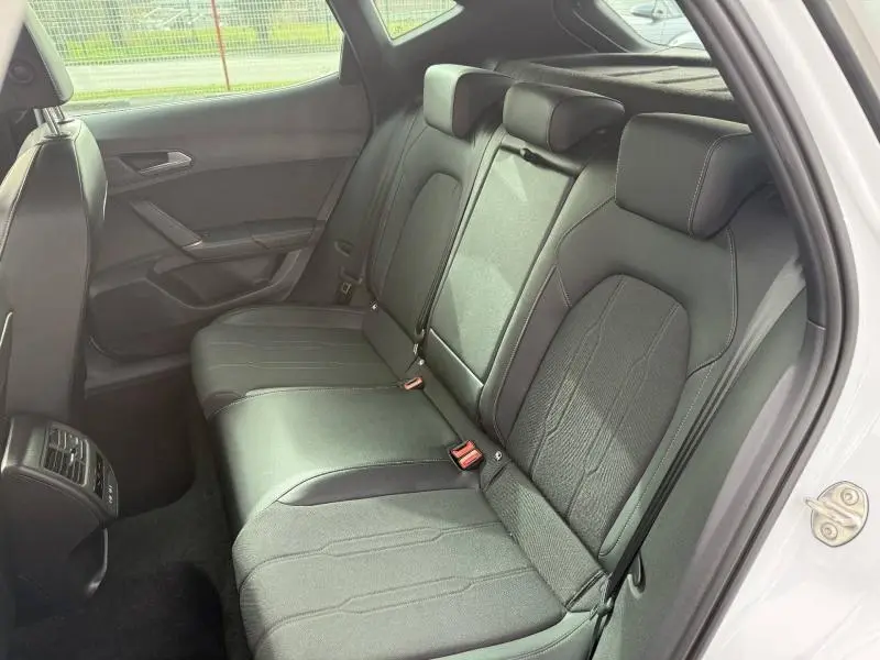 Vue intérieure du siège arrière côté droit du CUPRA Formentor blanc Nevada métallisé avec sellerie noire et ceintures visibles.