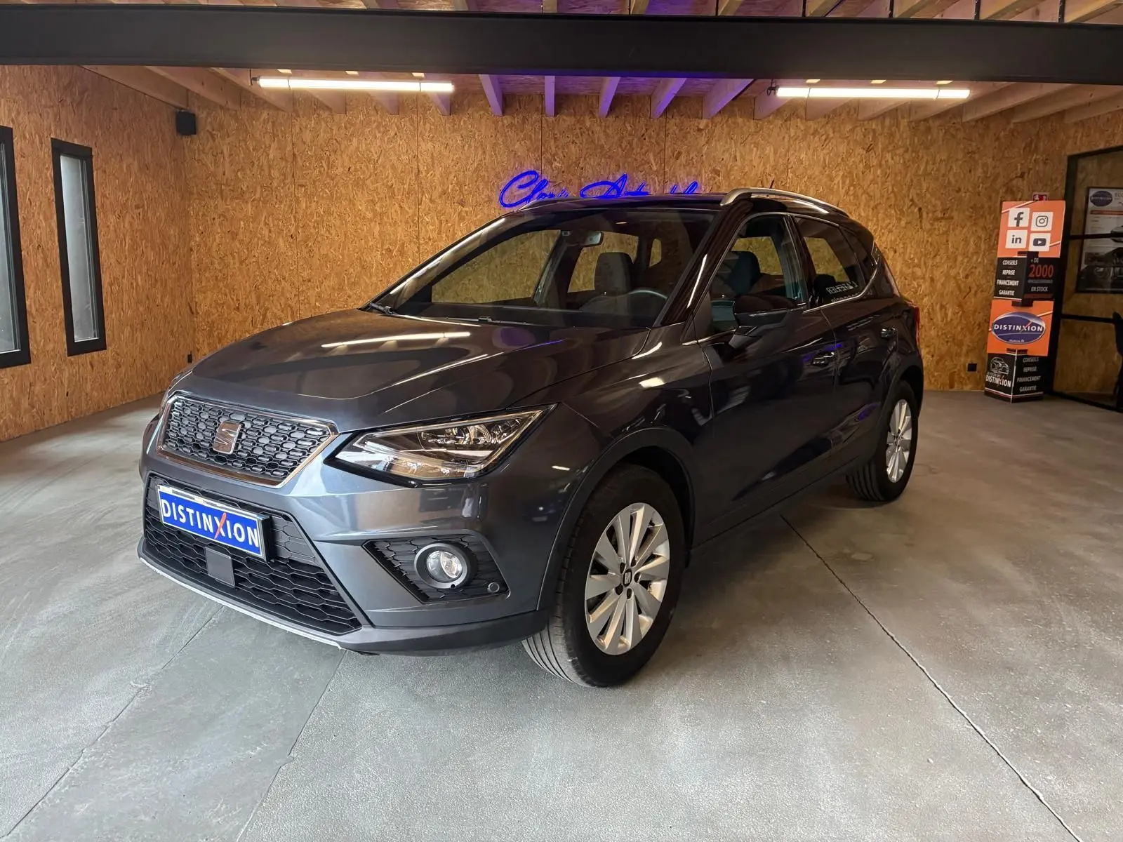SEAT Arona gris foncé en 3/4 avant droit dans un showroom avec éclairage intérieur et jantes argentées.