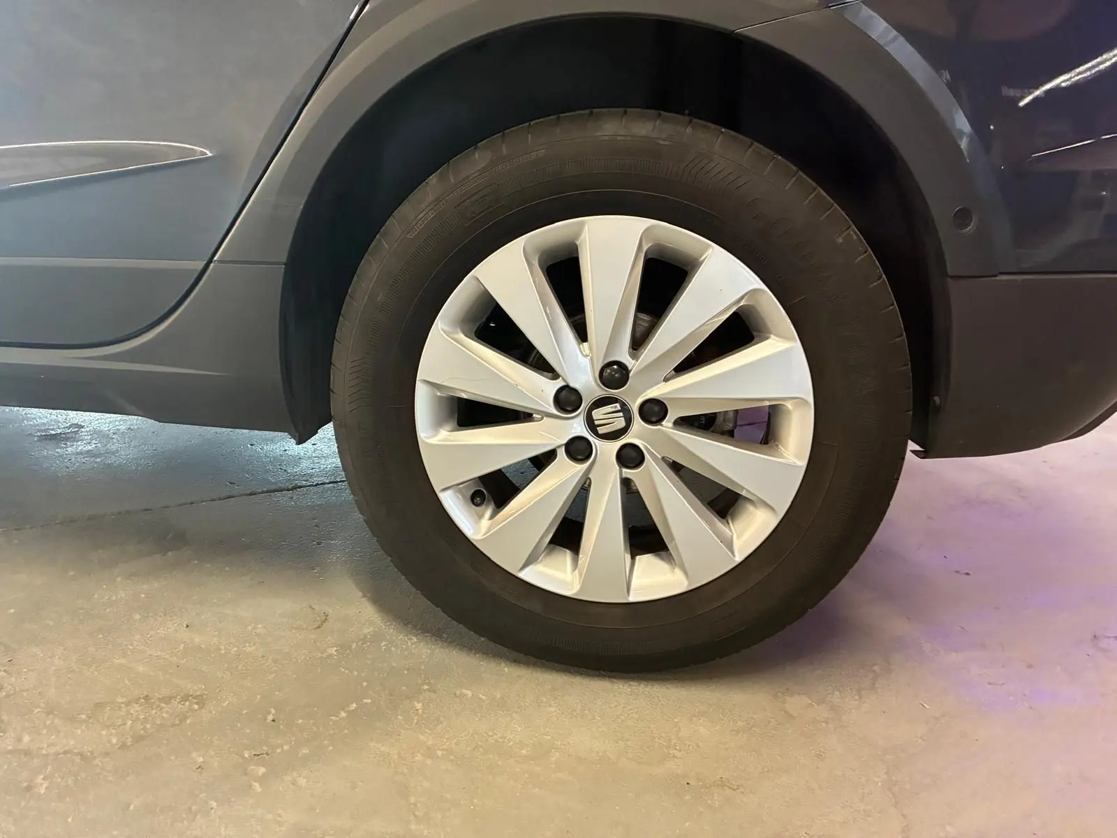 Gros plan sur la roue arrière droite d’un SEAT Arona gris foncé, mettant en valeur la jante alliage au design moderne.
