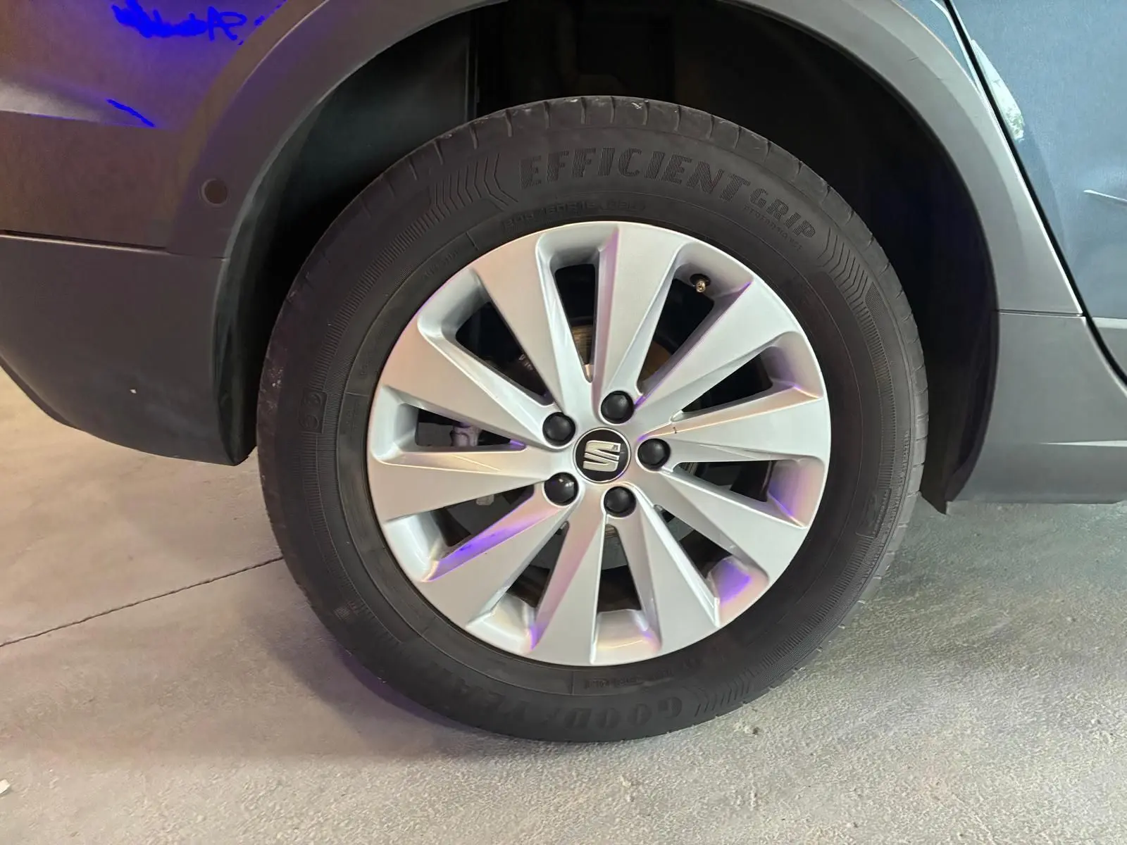 Gros plan sur la roue avant gauche d'un SEAT Arona gris foncé, avec jante alliage à dix branches et logo central.