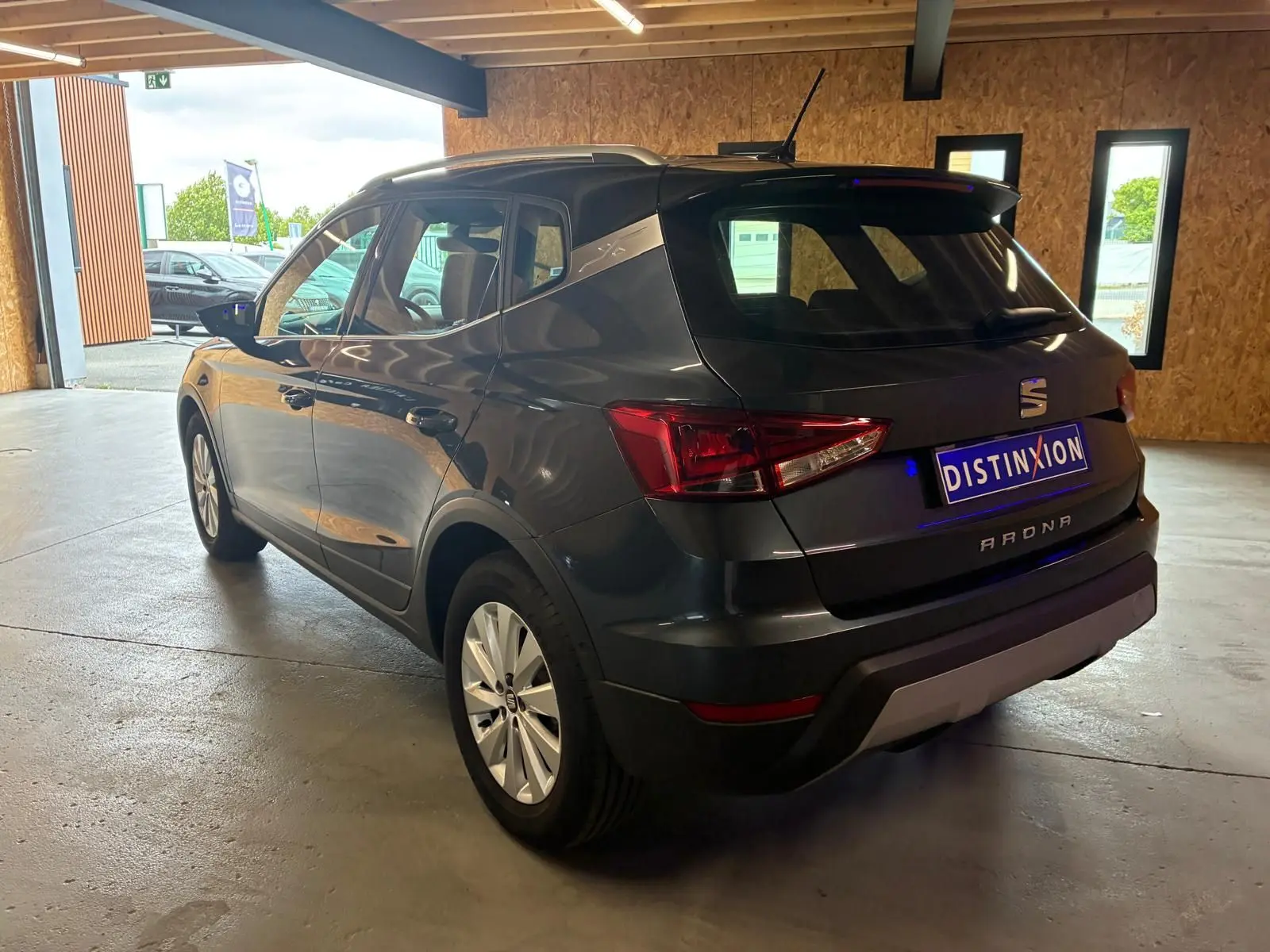 SEAT Arona gris foncé vue 3/4 arrière droit, avec jantes alliage et toit noir contrasté dans un garage.