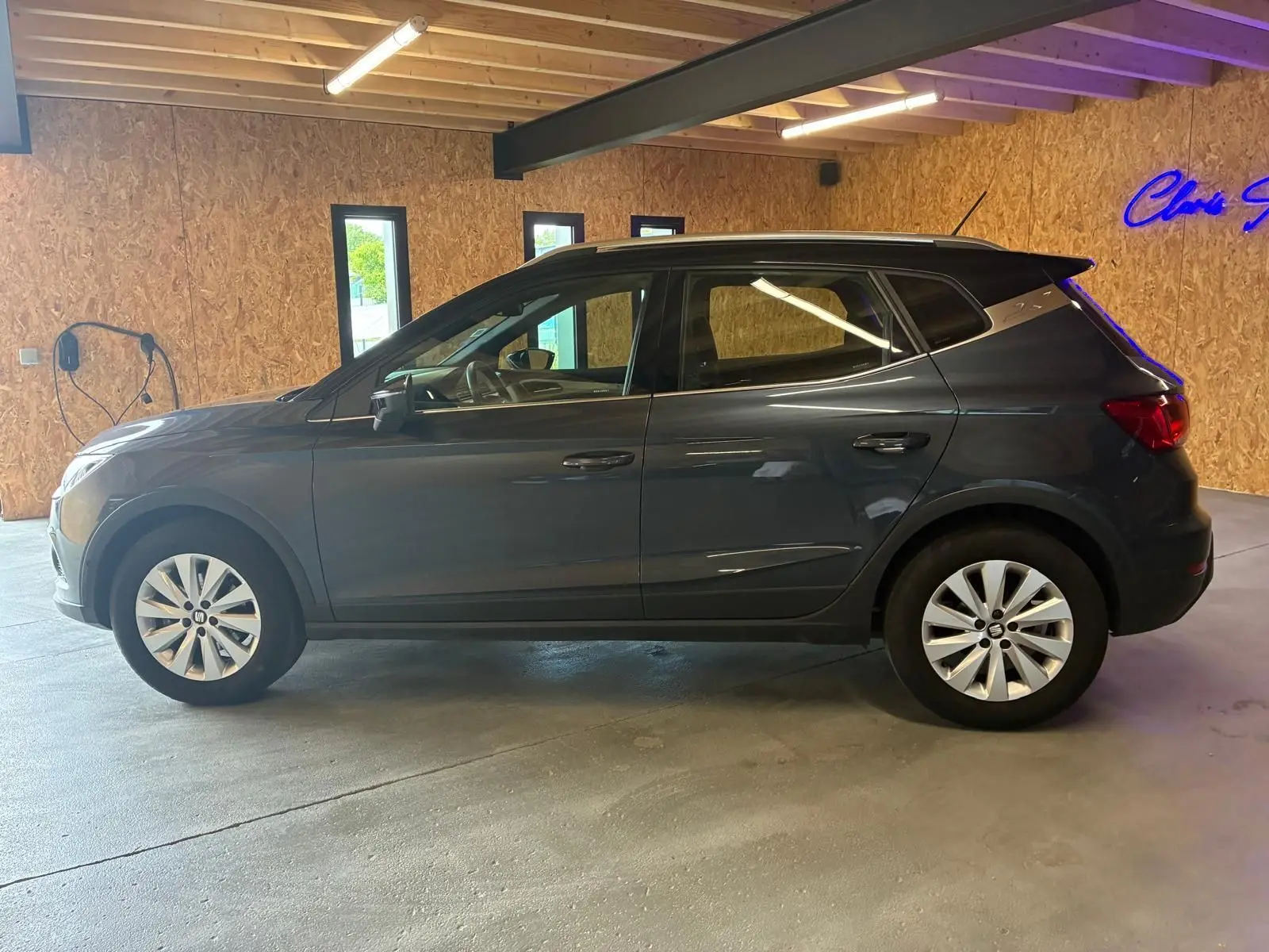 SEAT Arona gris foncé vue de profil côté gauche, avec jantes alliage et toit noir dans un garage.