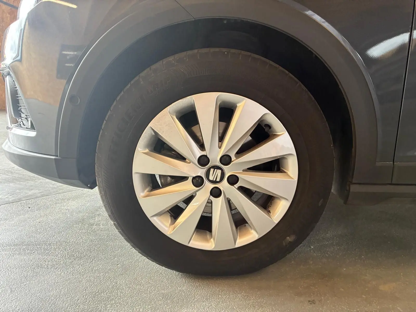 Gros plan sur la roue avant droite d’un SEAT Arona gris foncé, mettant en valeur la jante alliage à rayons fins.